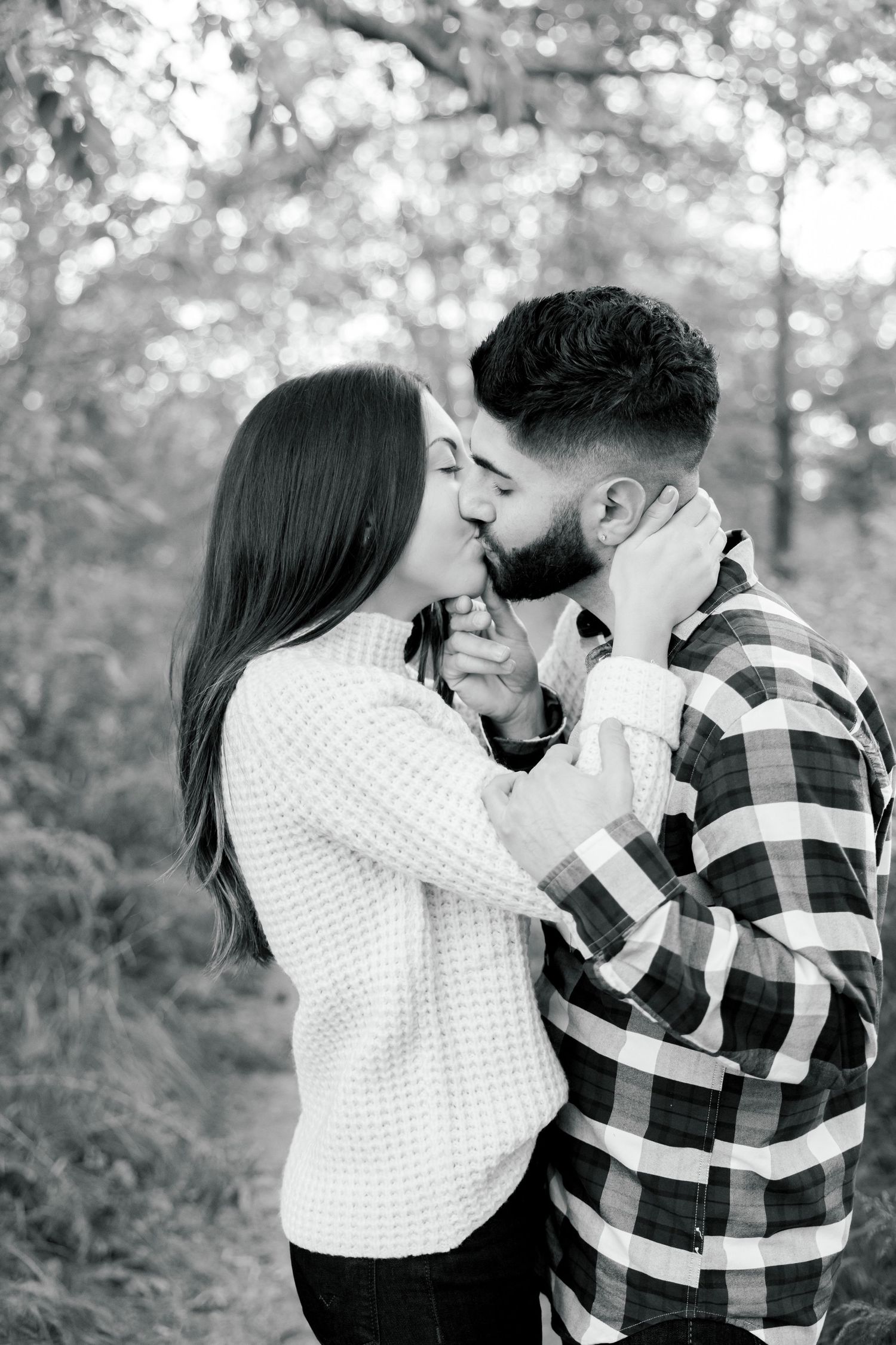 Black and white romantic portrait in wooded setting with natural bokeh background.