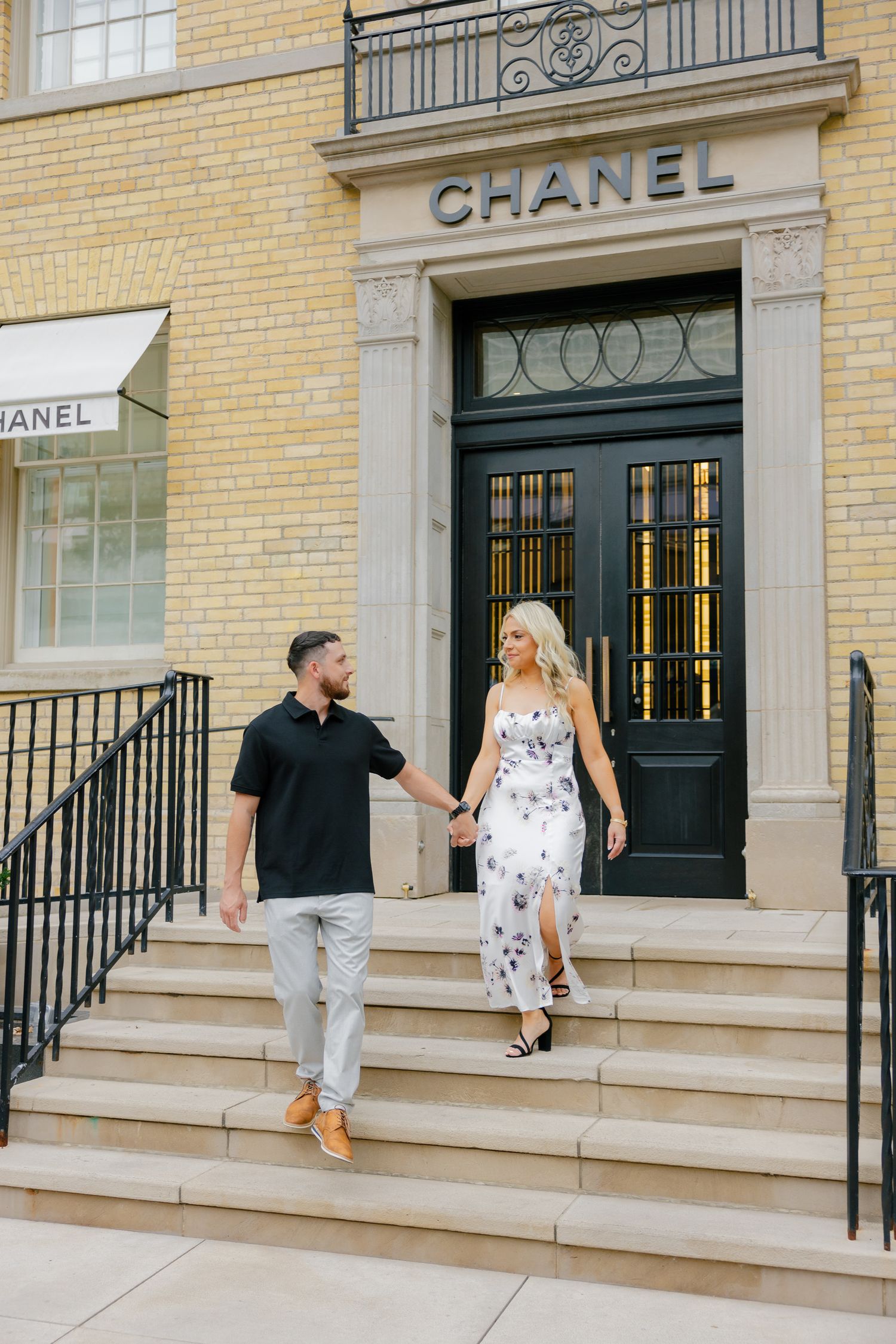 Fashionable pair walking down the steps of a Chanel boutique entrance.