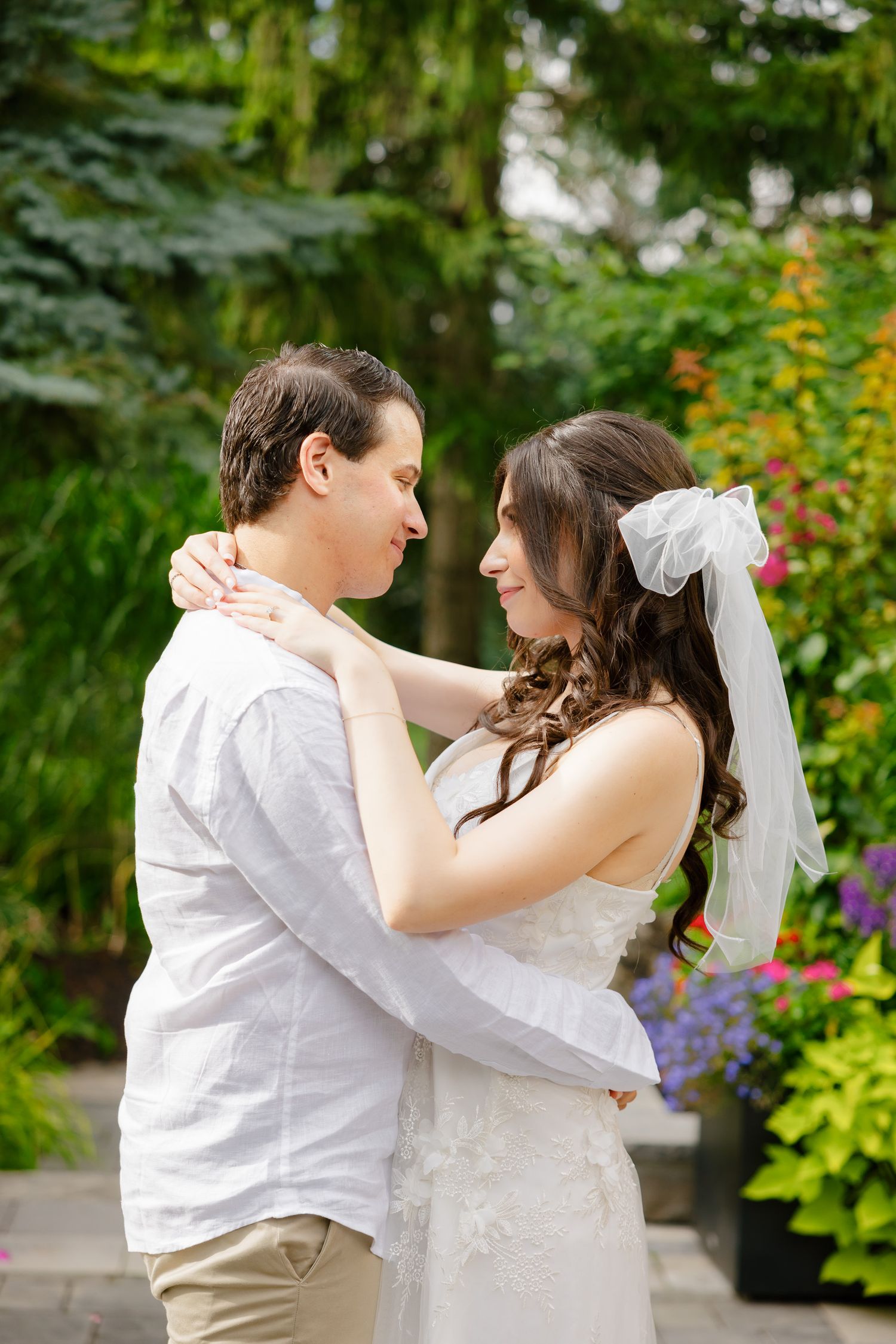 A tender embrace between newlyweds in a lush garden setting with colorful flowers and greenery.