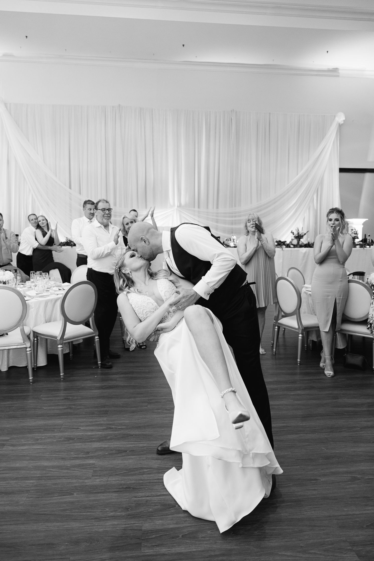 Black and white photo of romantic dip during wedding dance at reception.