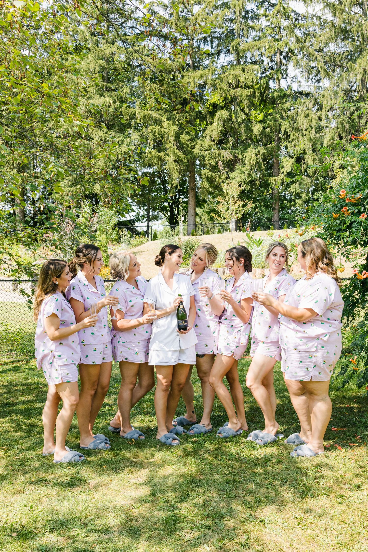 Group wearing matching floral robes and white shorts celebrate together in a sunny garden setting.