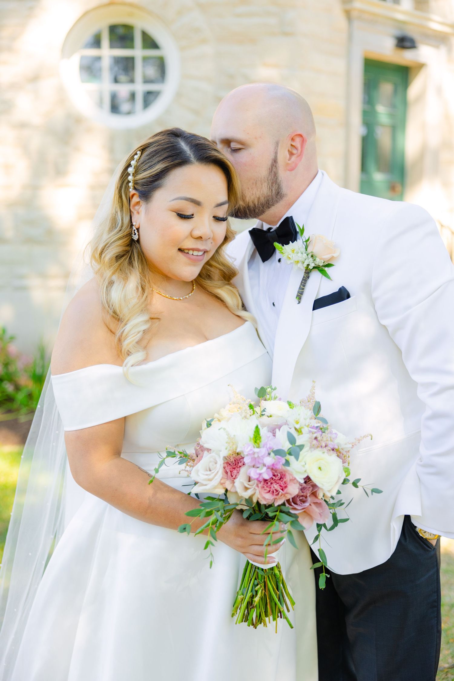 An intimate wedding portrait captures a tender moment between the couple with a beautiful floral bouquet.