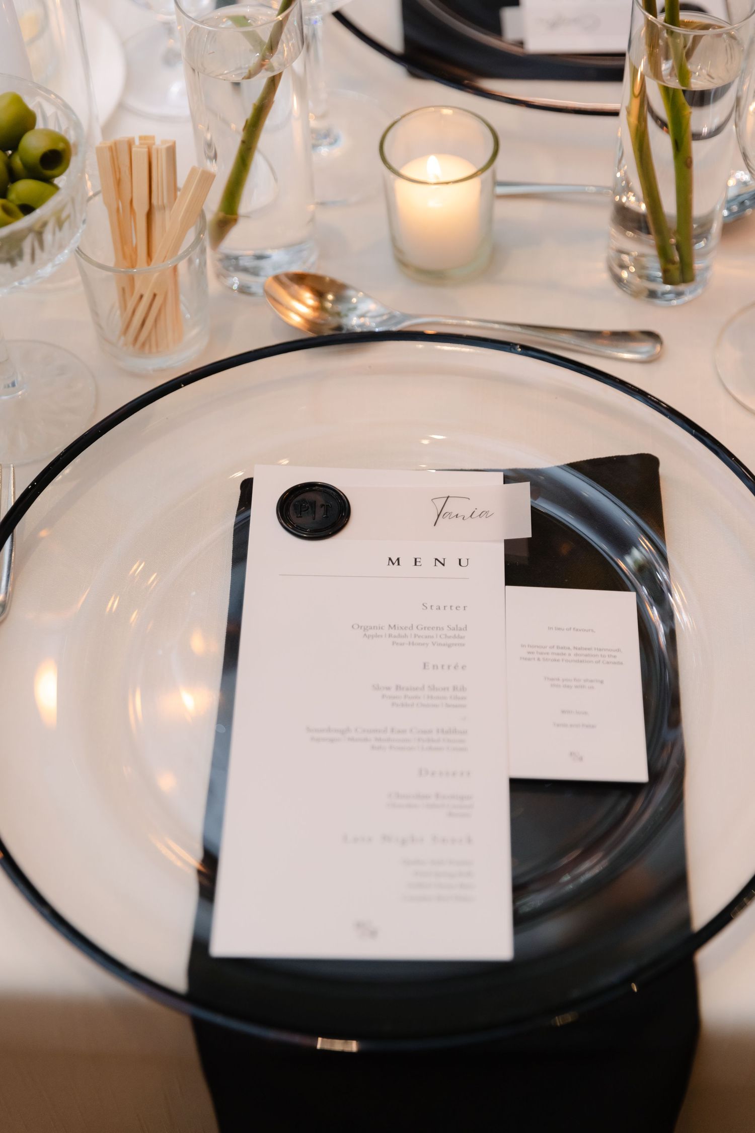 Minimalist place setting with menu card, white plate, and votive candle.
