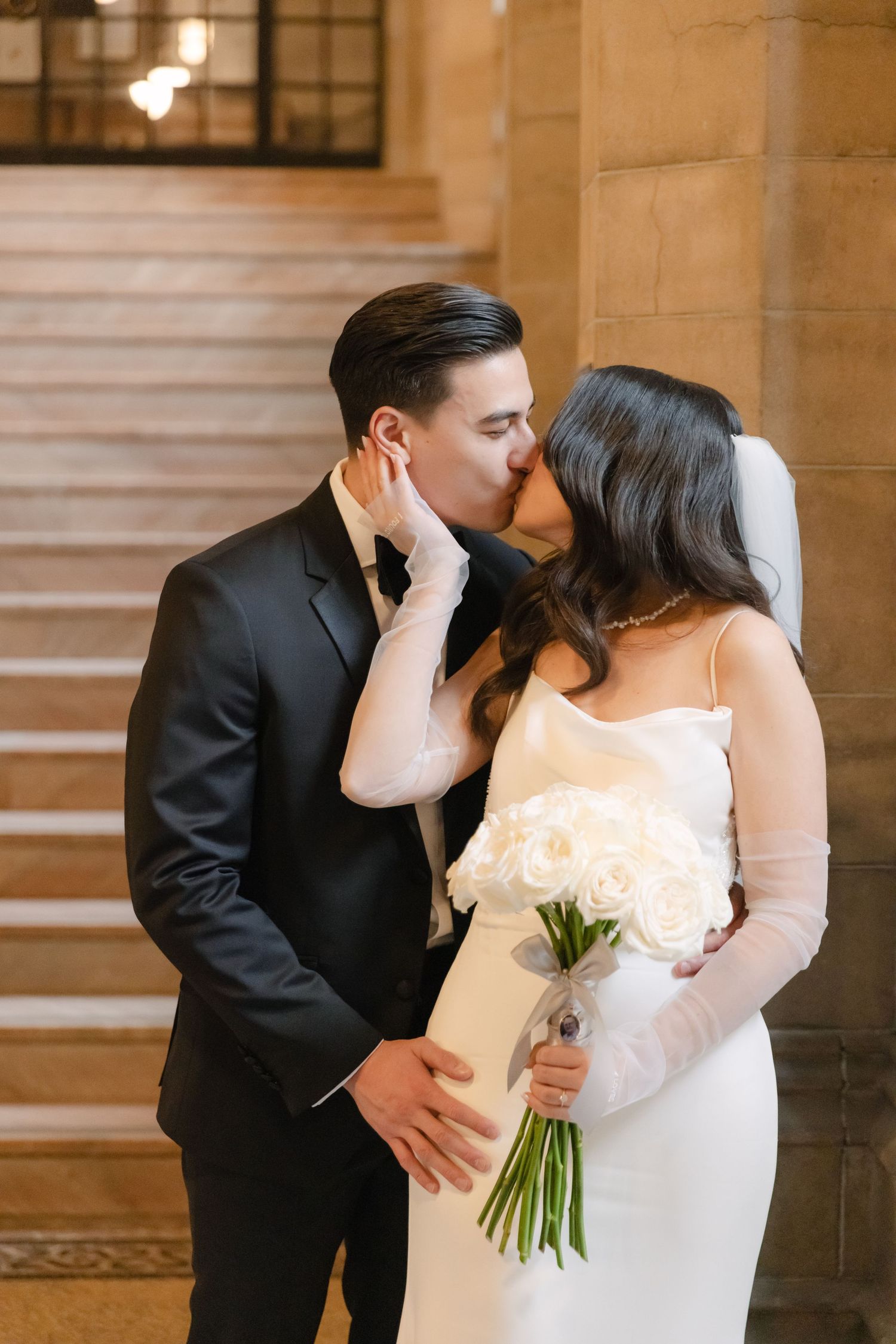 Tender moment between newlyweds with bride holding white floral bouquet.