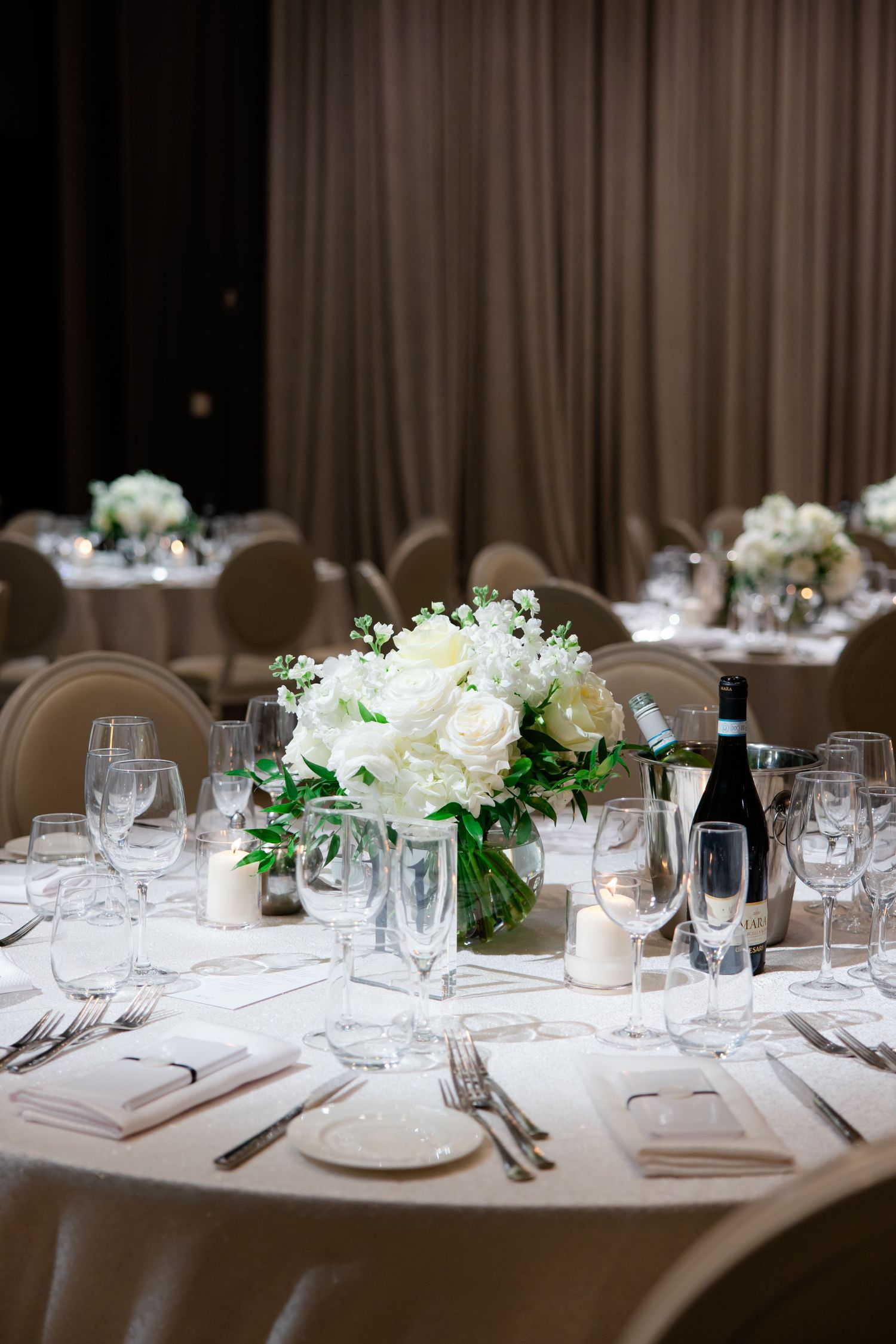 Elegant round dining table set with white floral centerpiece and formal place settings.