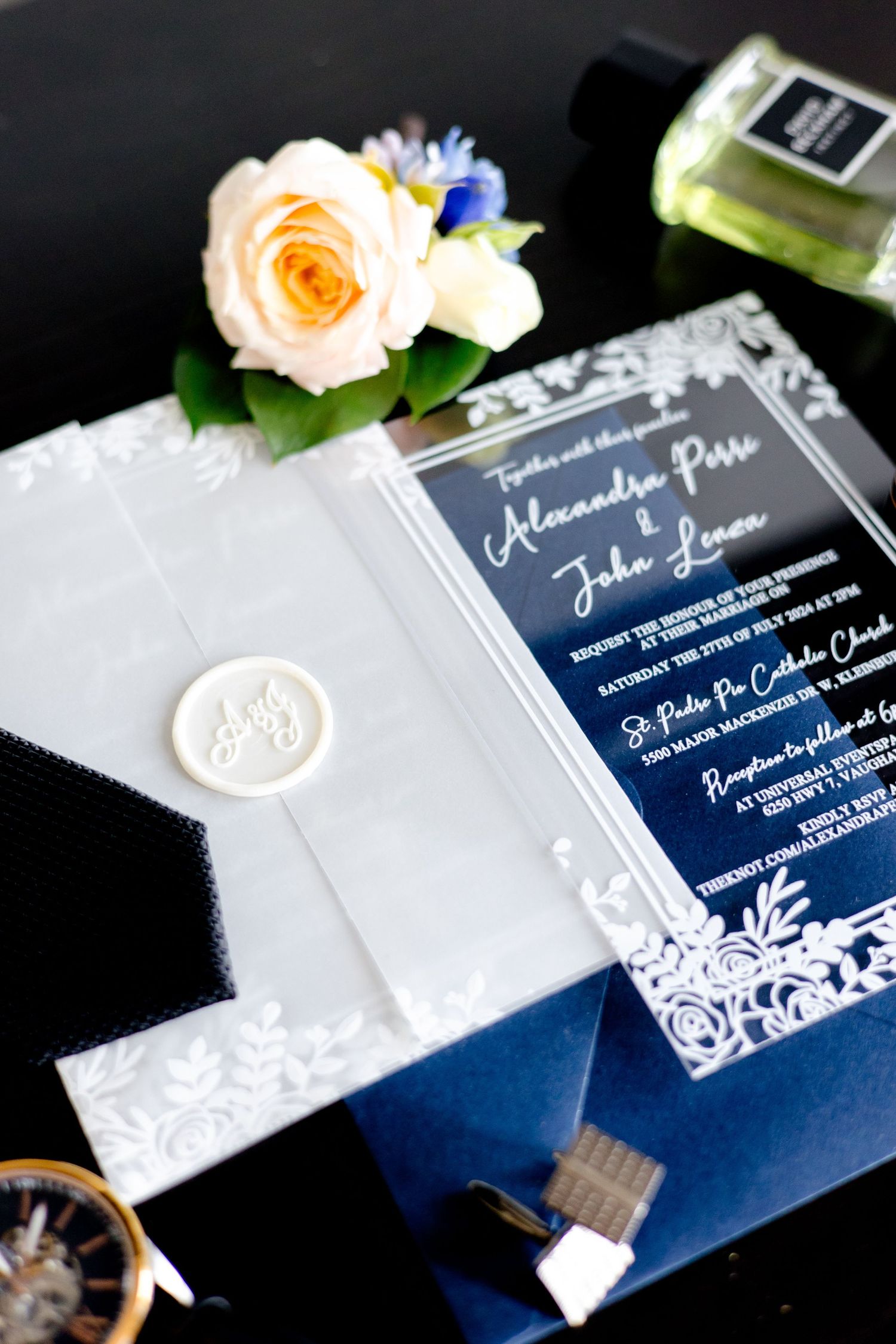 Wedding invitation with navy blue ombre design and white wax seal next to peach rose.