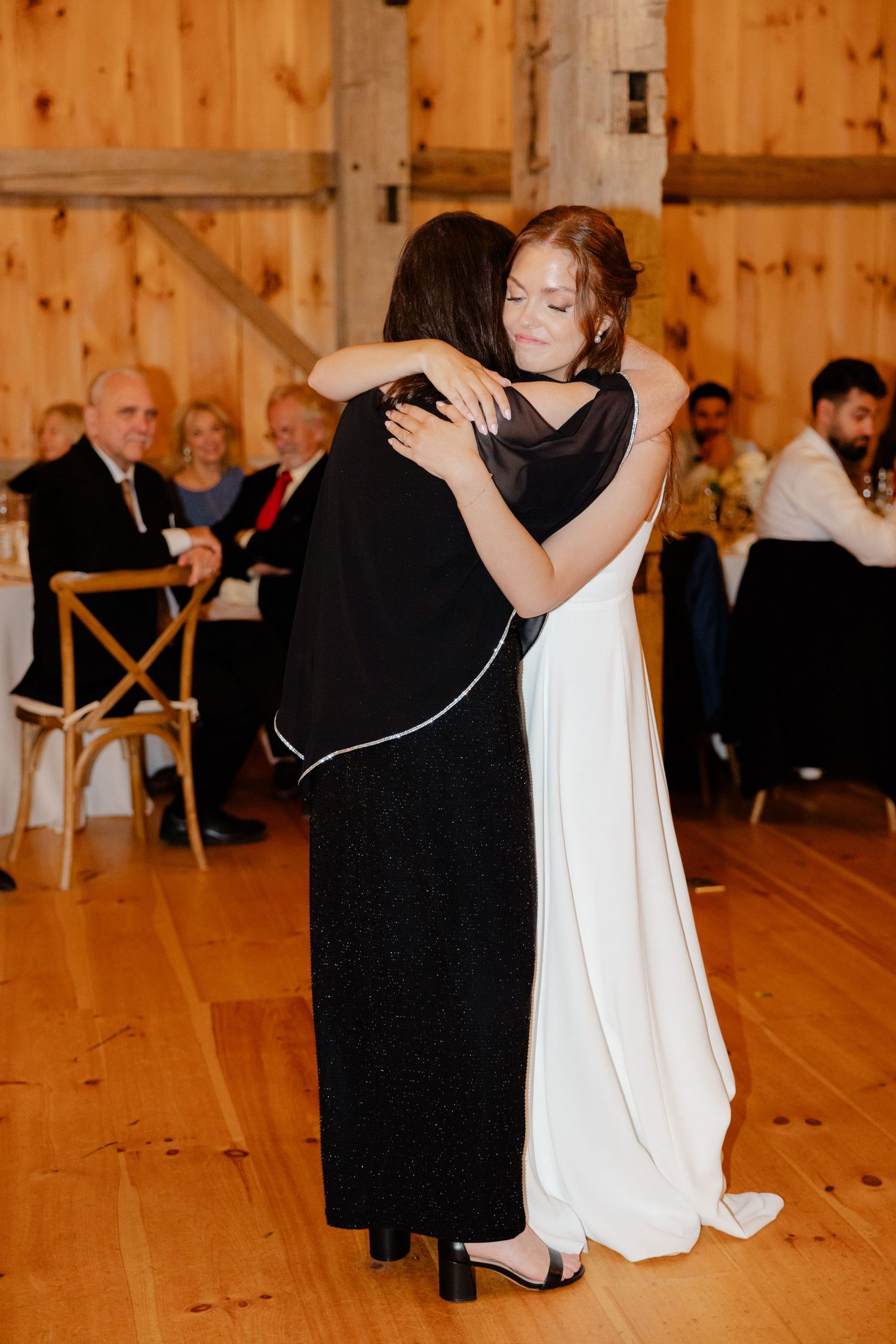 A wedding dance moment between two people in formal attire on a wooden dance floor.