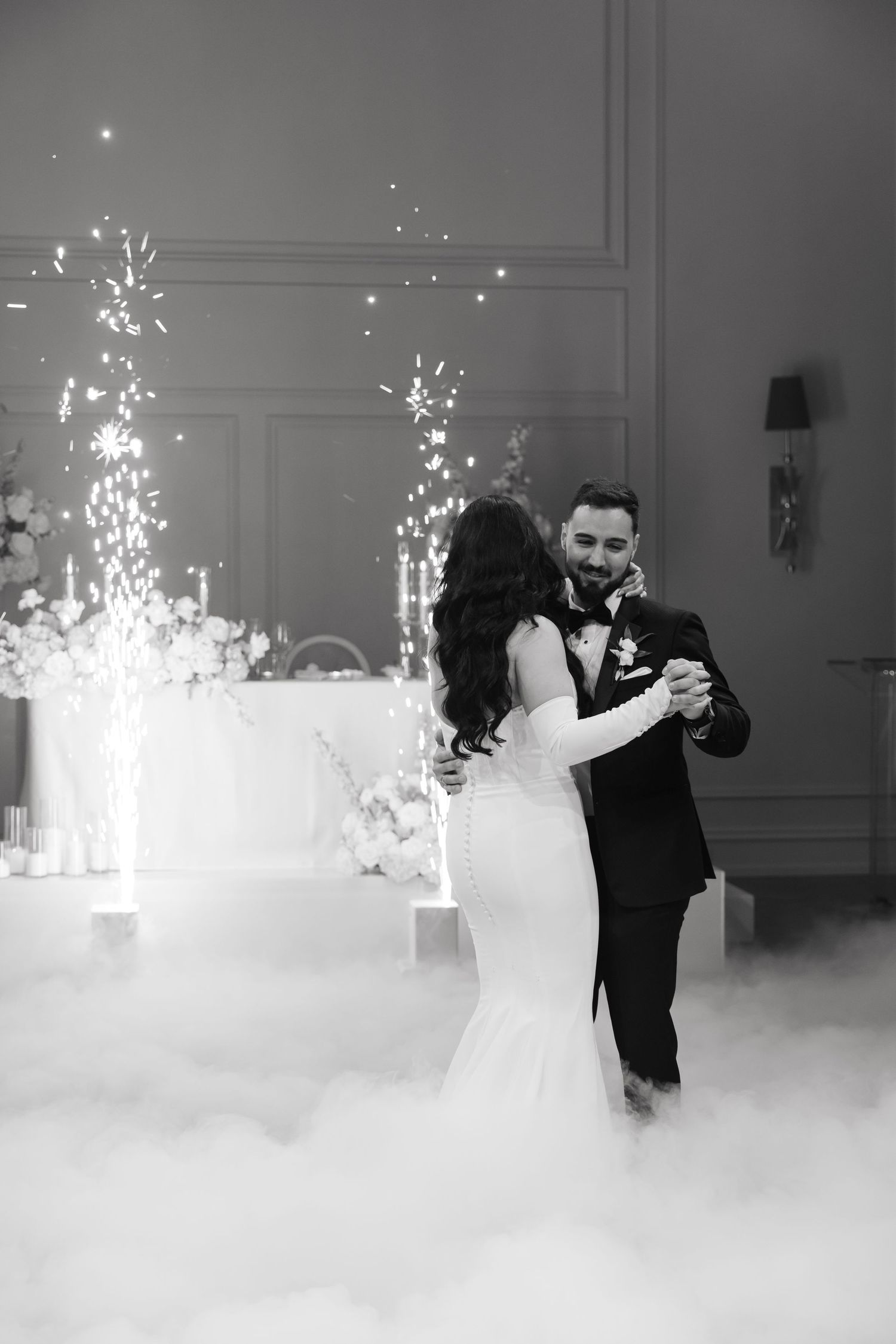 Couple shares intimate dance moment with sparklers and fog effects creating magical atmosphere.