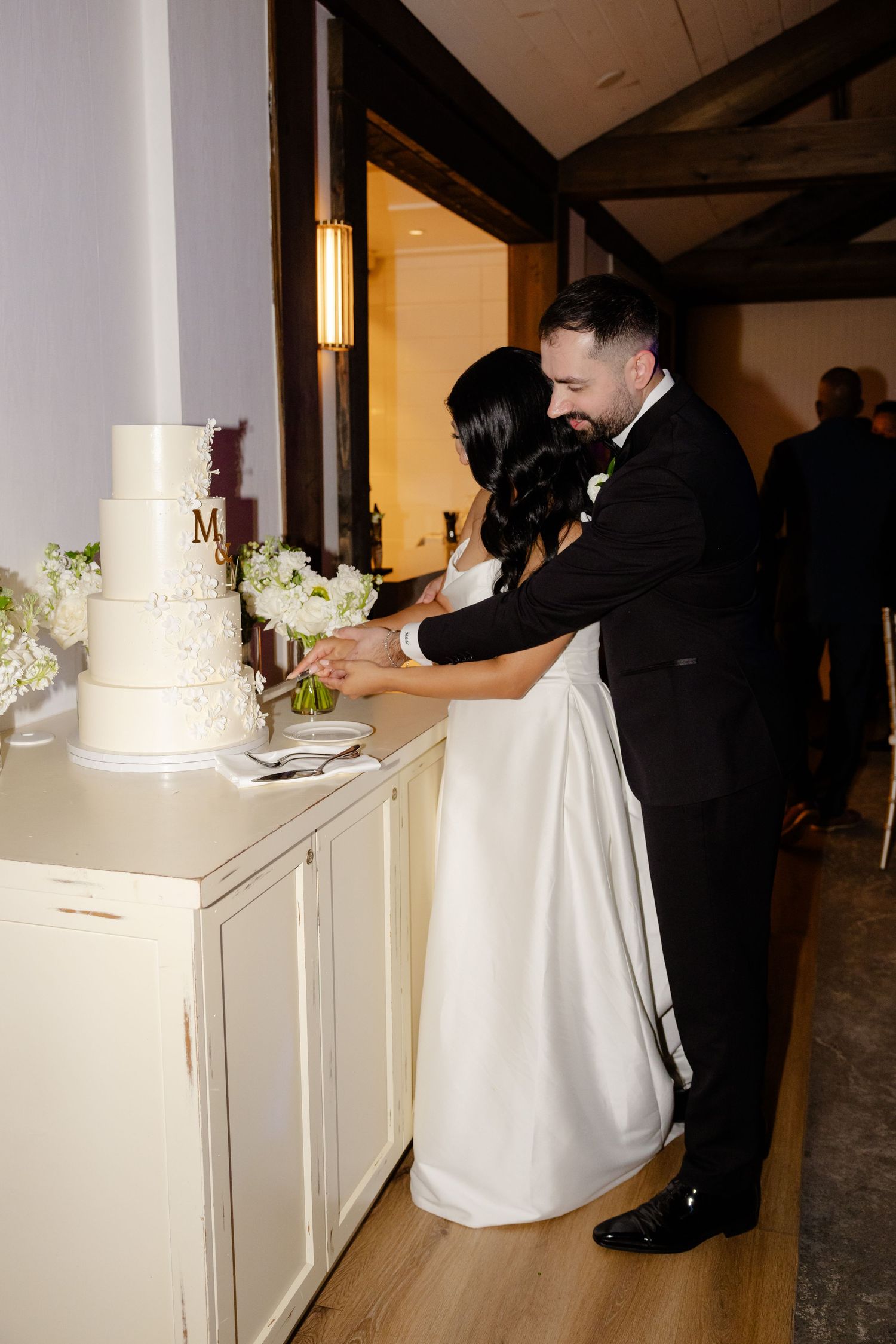 Couple cutting their elegant white wedding cake at reception.