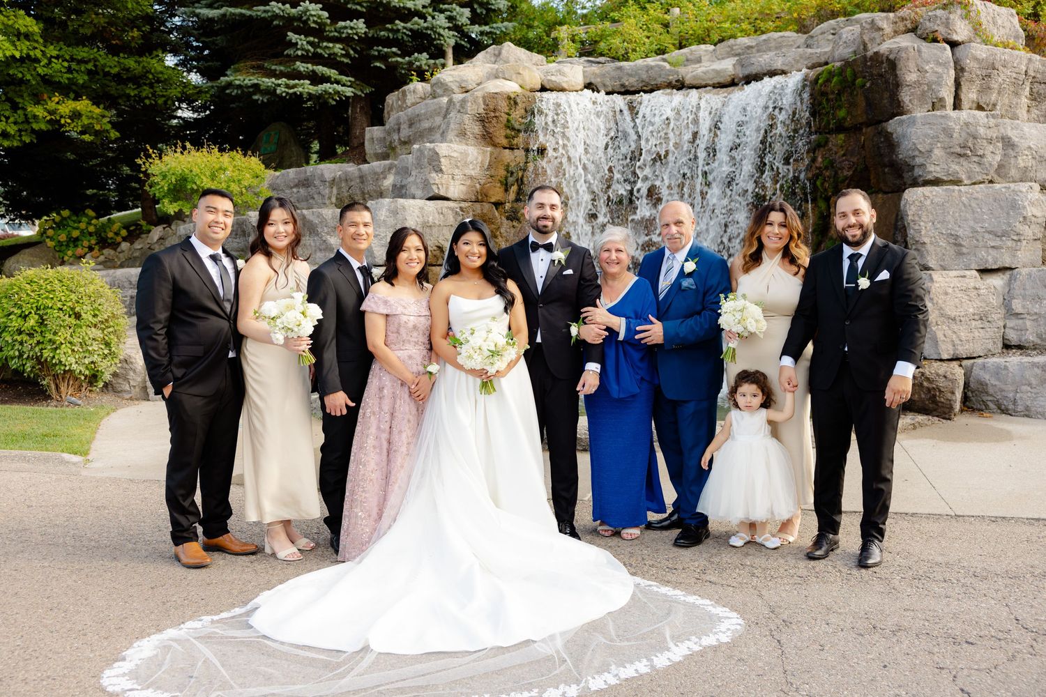 Wedding party formal portrait in front of stone waterfall backdrop outdoors.