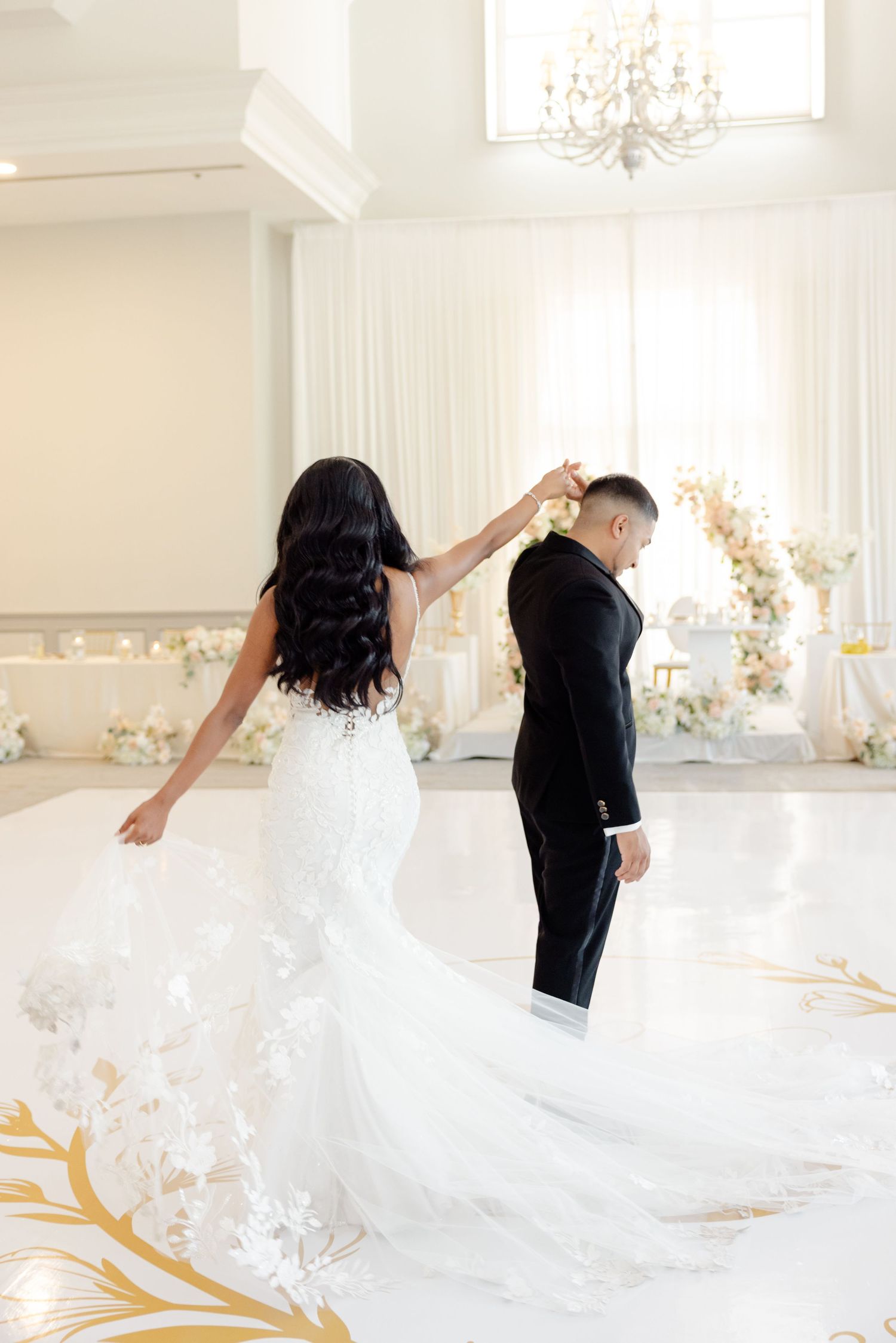 Wedding couple dancing on custom gold monogram floor with bride's dress flowing.