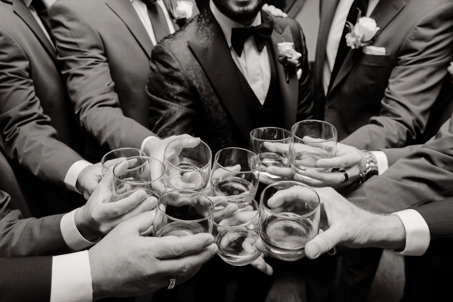 Multiple hands toasting with crystal glasses at formal celebration.
