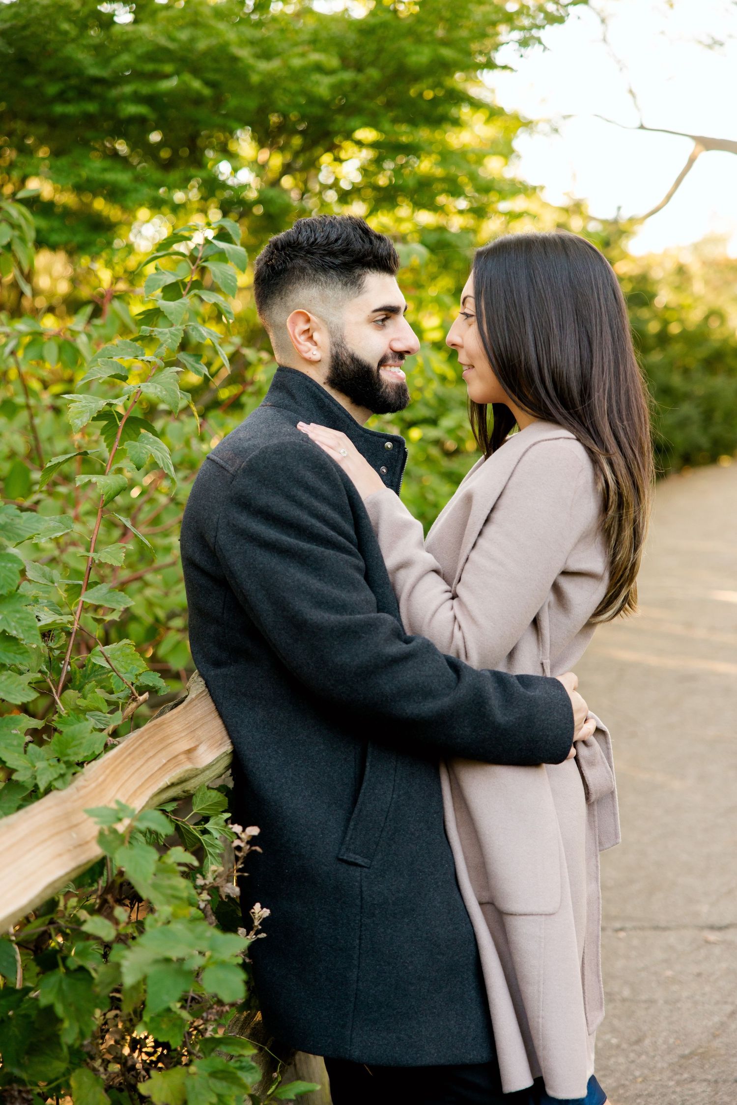 Happy couple embracing and laughing together in a sunlit garden setting.