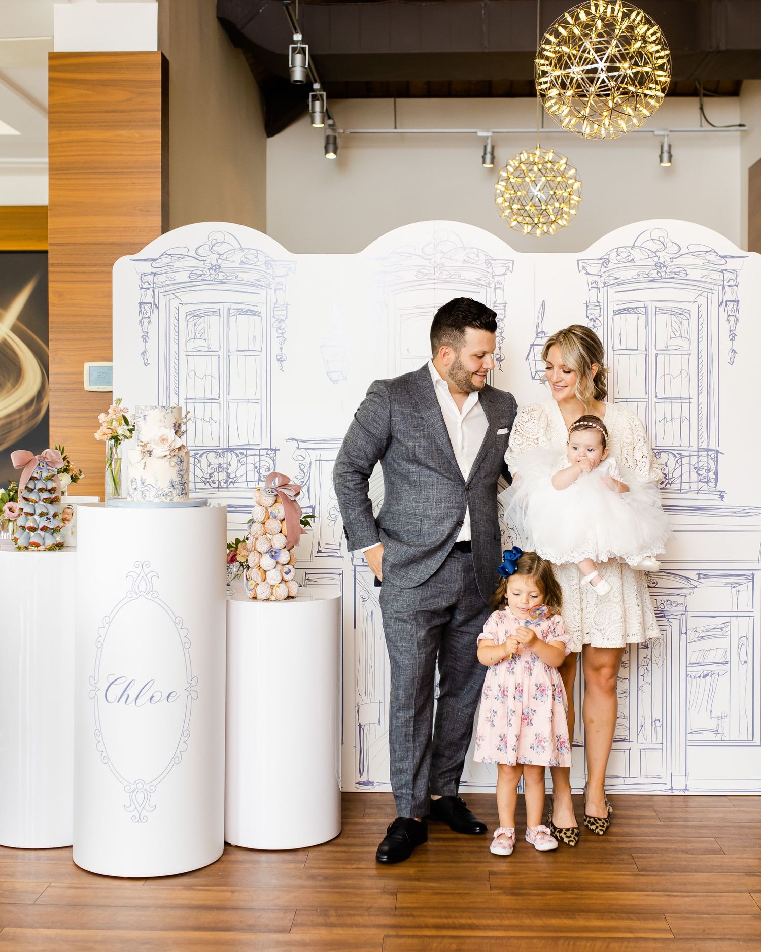 Elegant party setup with white columns and decorative lighting against a custom backdrop.