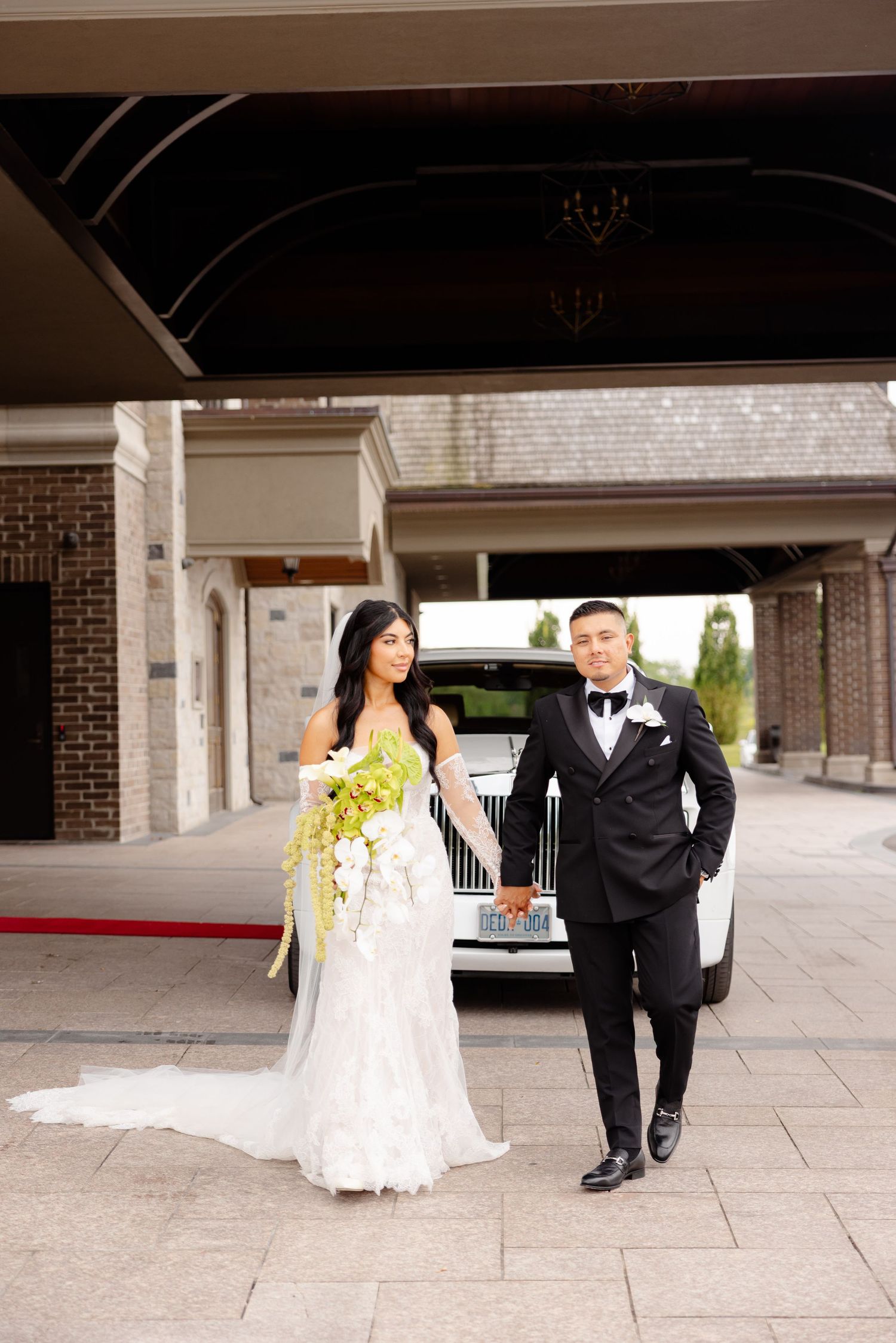 A bride and groom share a playful moment running together under an outdoor archway.