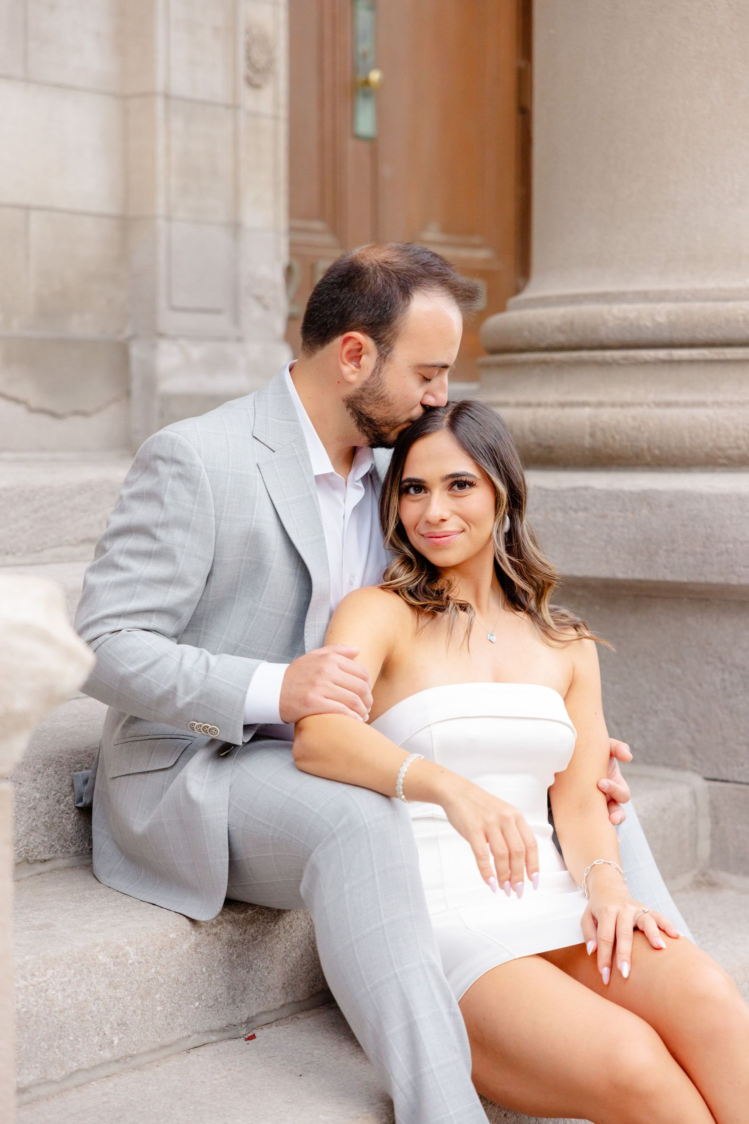 Intimate portrait on stone steps showcasing formal attire against classical architecture.