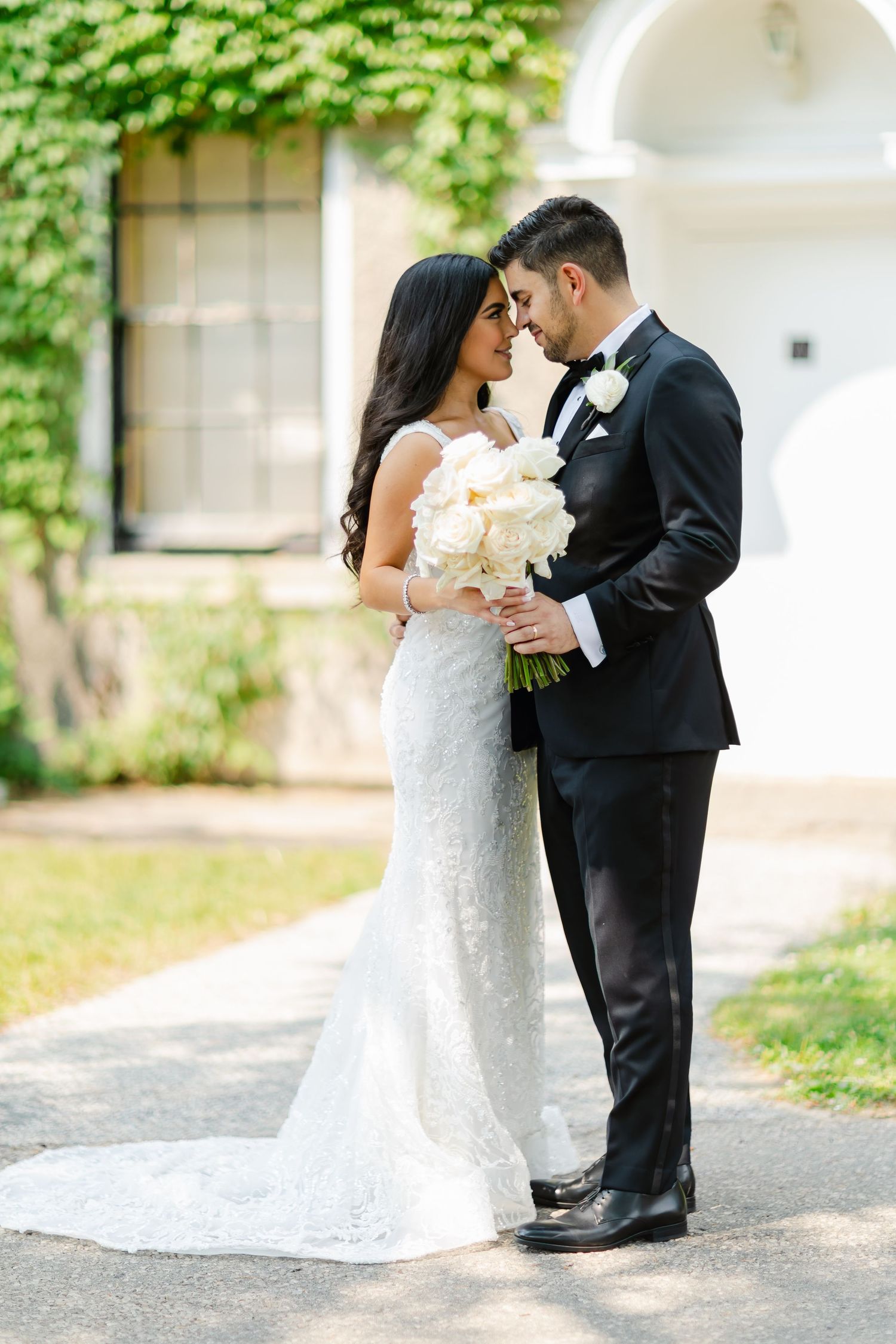 Tender wedding moment captured in front of a classical archway with climbing ivy.