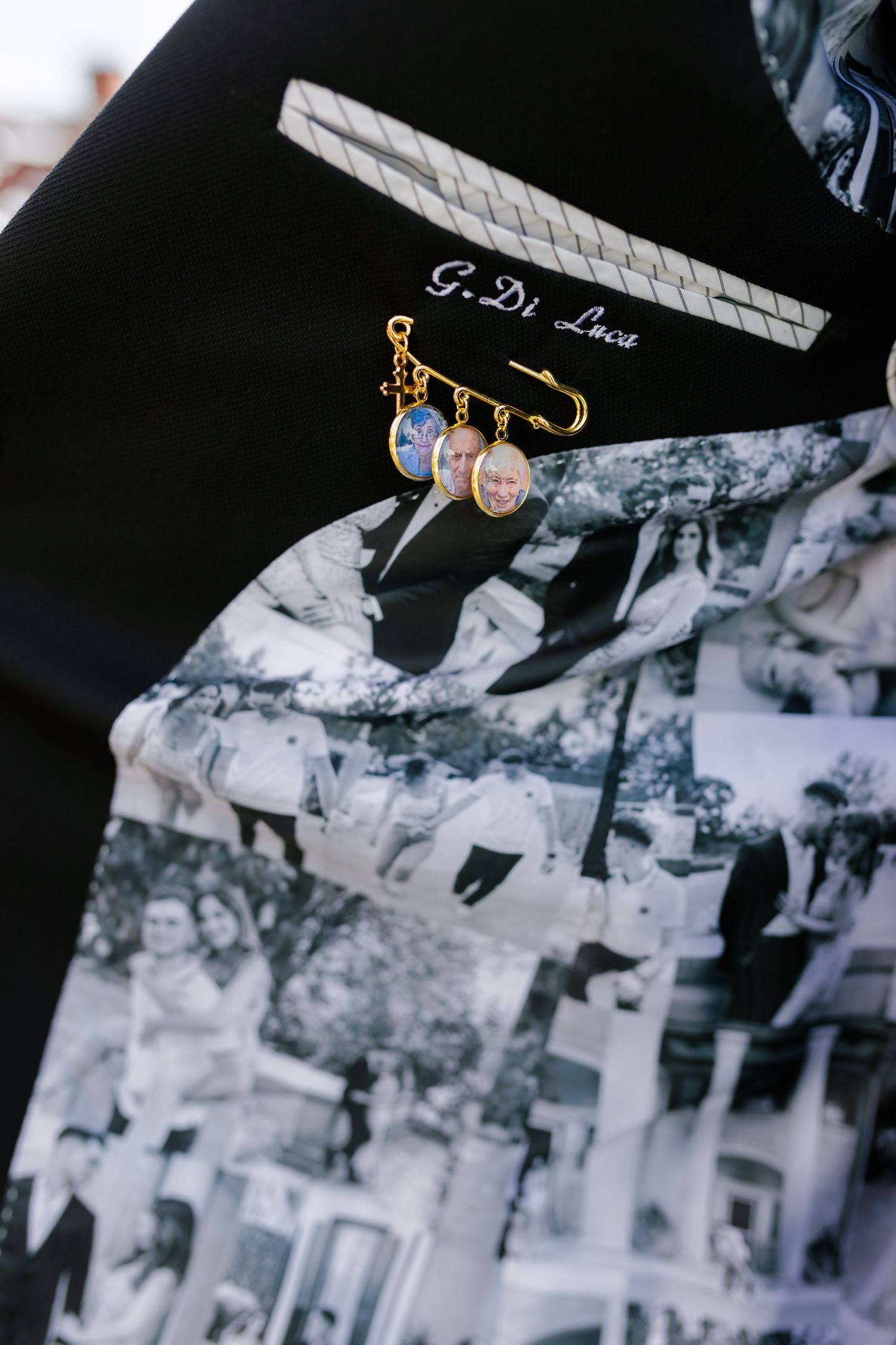 A decorative safety pin with colorful charms displayed on a black fabric with photos.