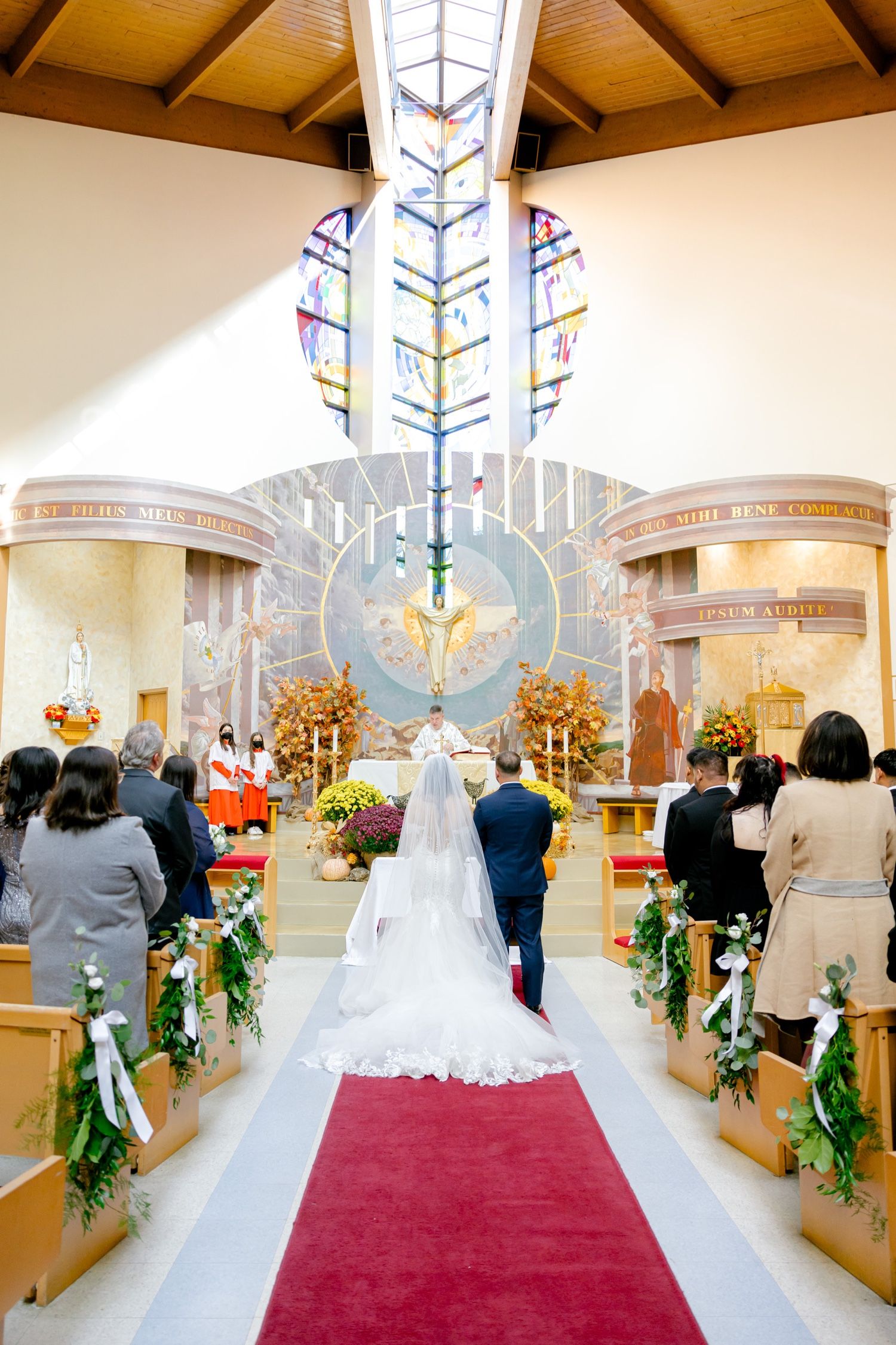 Church wedding ceremony with stunning stained glass backdrop and golden altar decorations.