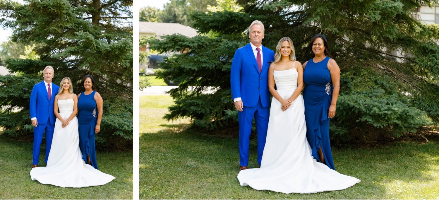 Wedding party members pose together in coordinated white and royal blue attire against evergreen backdrop.