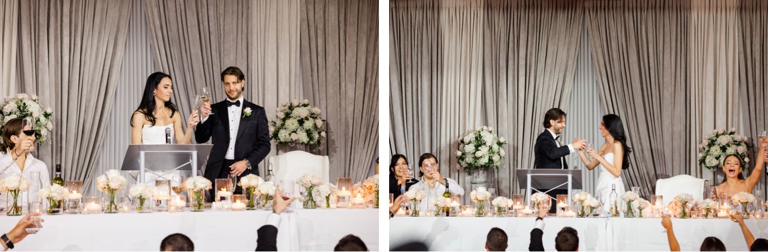 Wedding reception scene with toast speeches at head table decorated with floral arrangements.