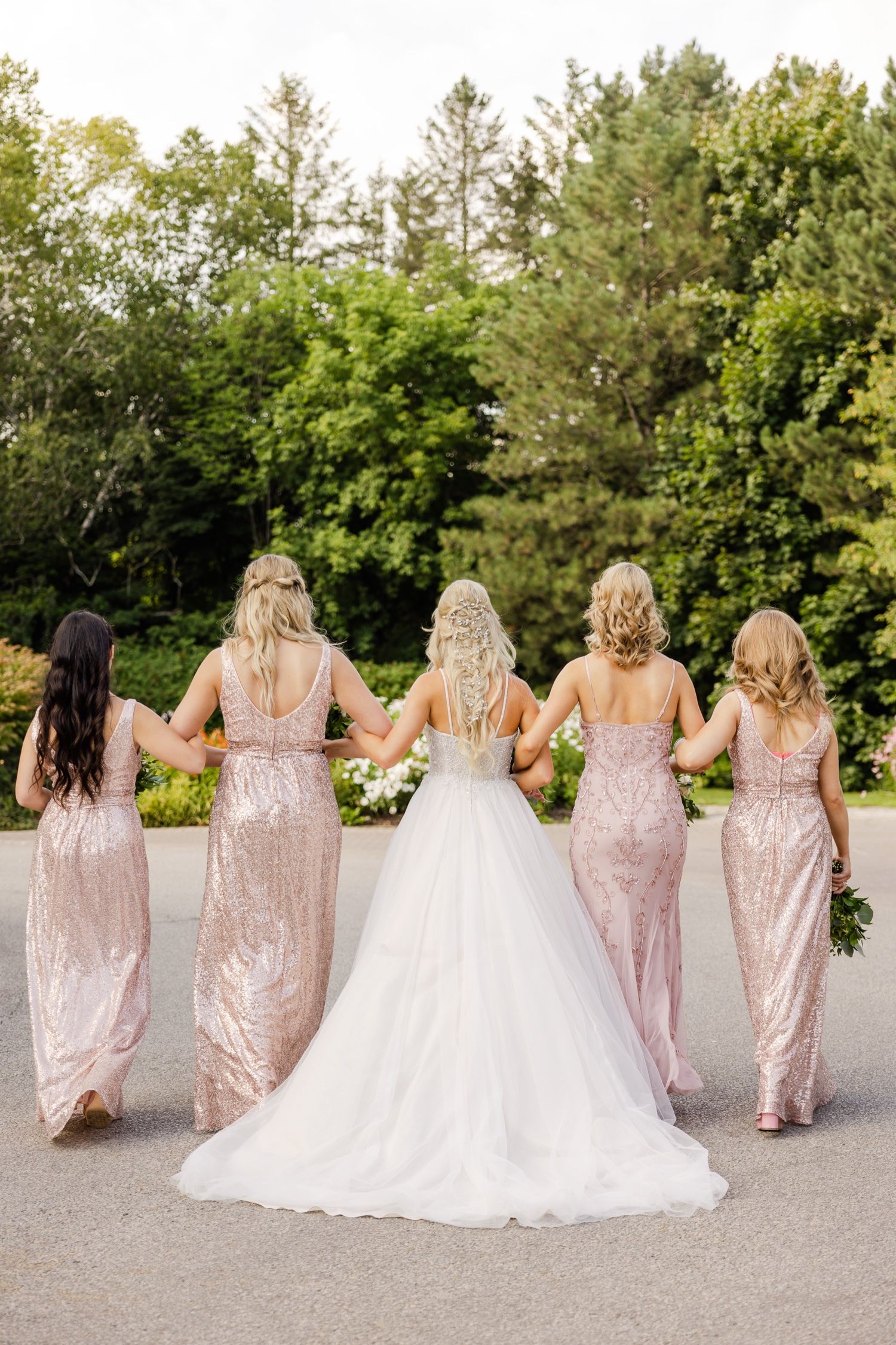 Wedding party walking away showing back view of pink sequin dresses and white wedding gown.