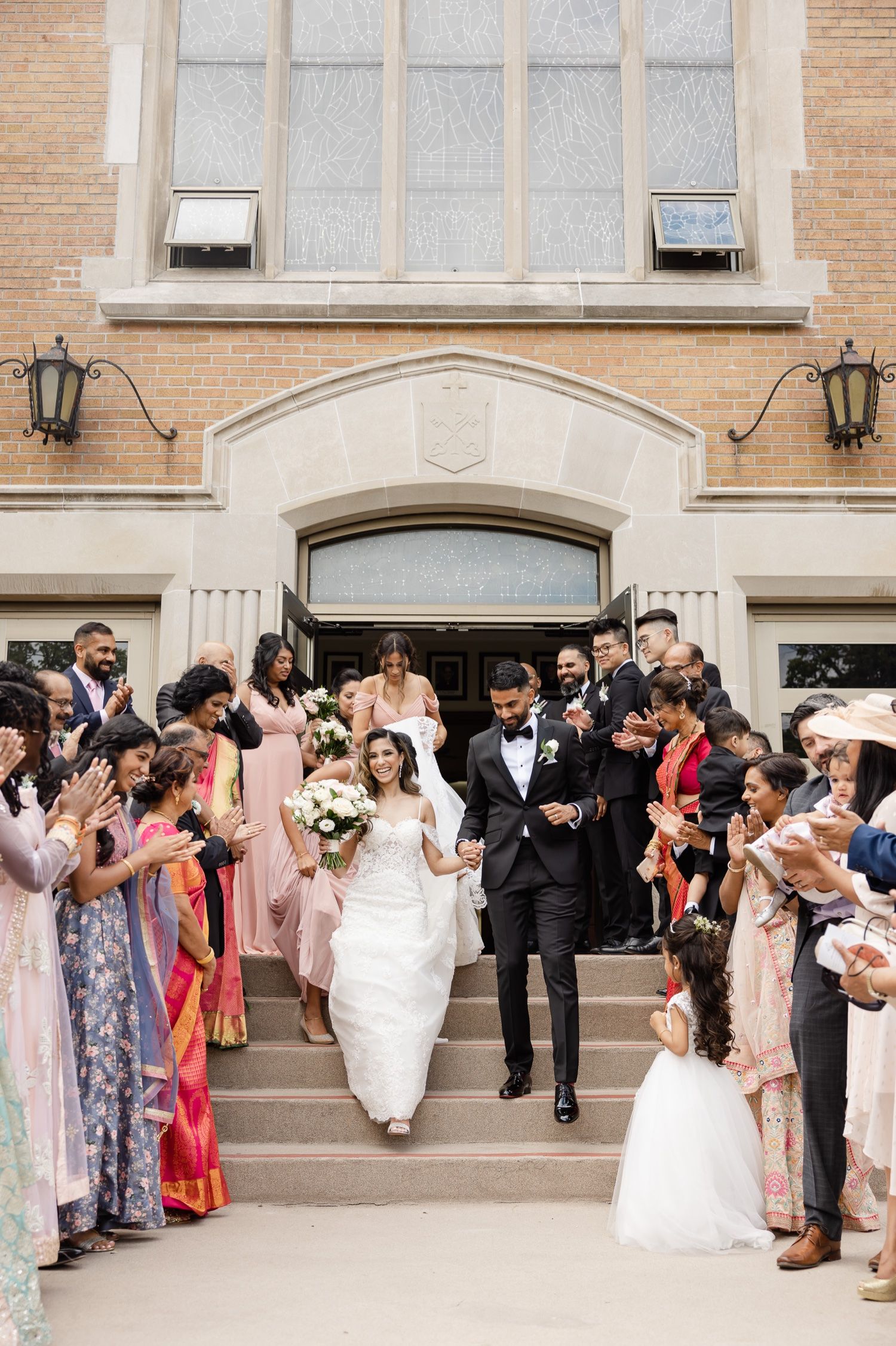 Newlyweds exit church while guests line the steps in celebration.
