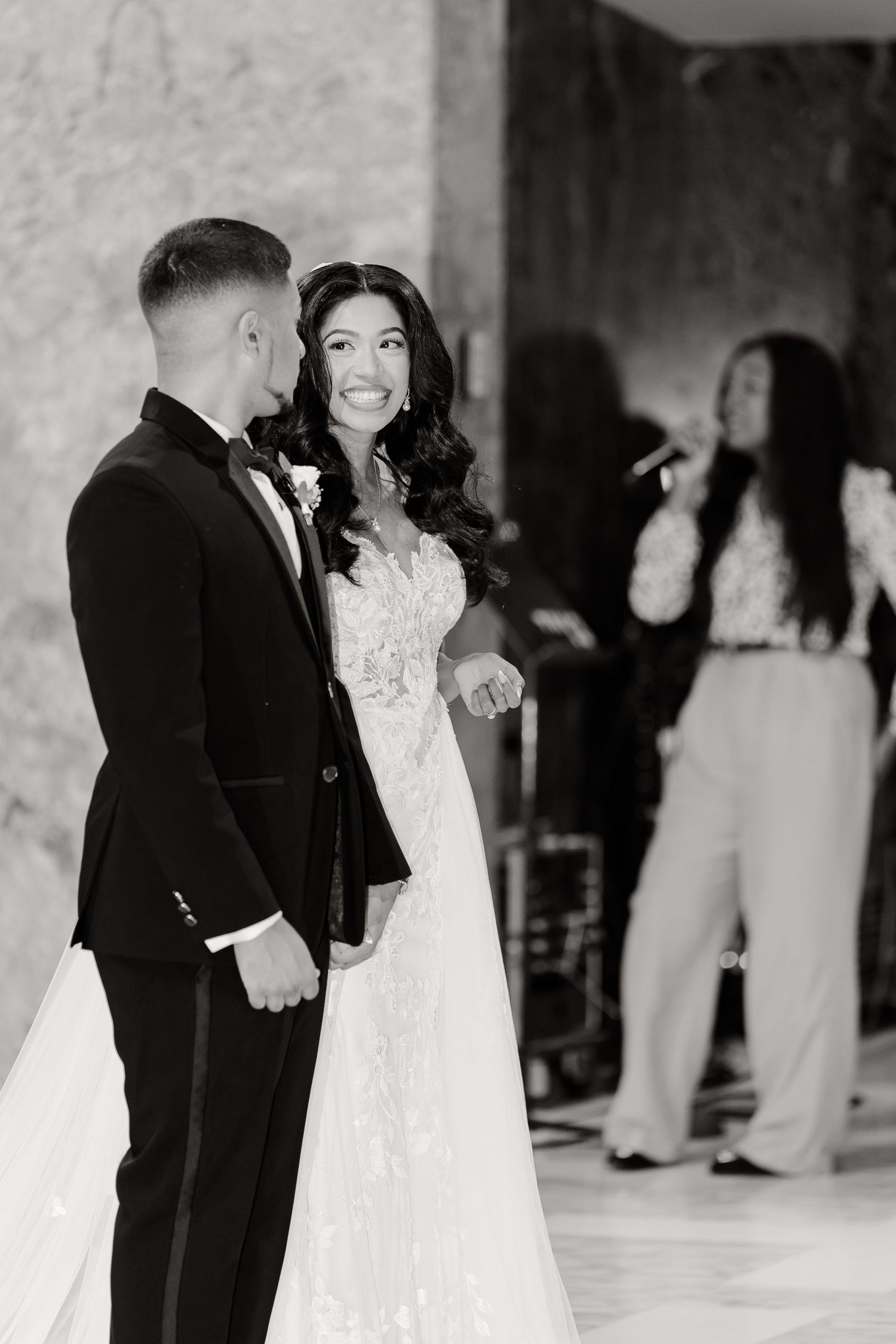 Black and white candid moment captured between newlyweds during wedding reception.