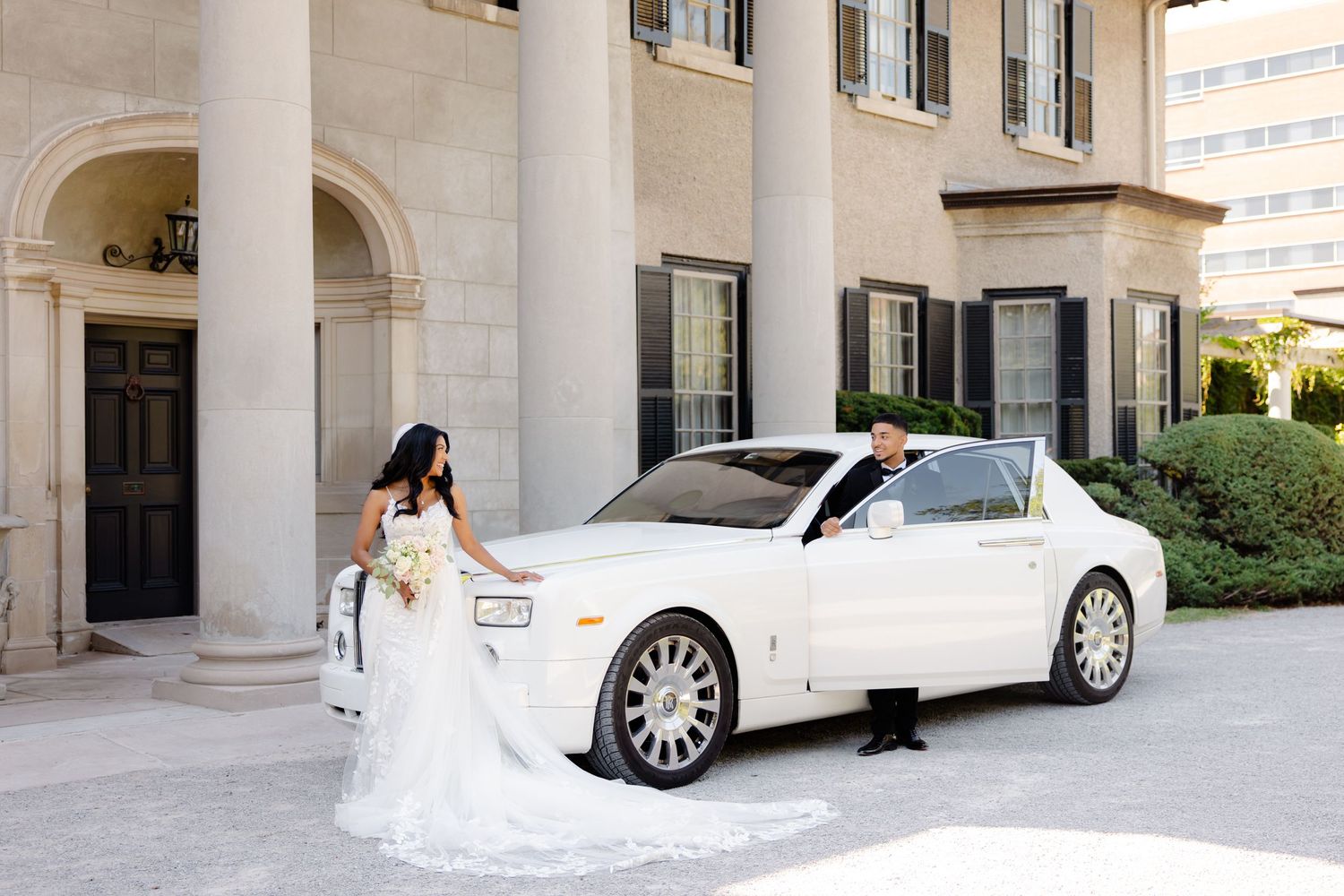 Wedding photo featuring a luxury white car and elegant architecture with columns.