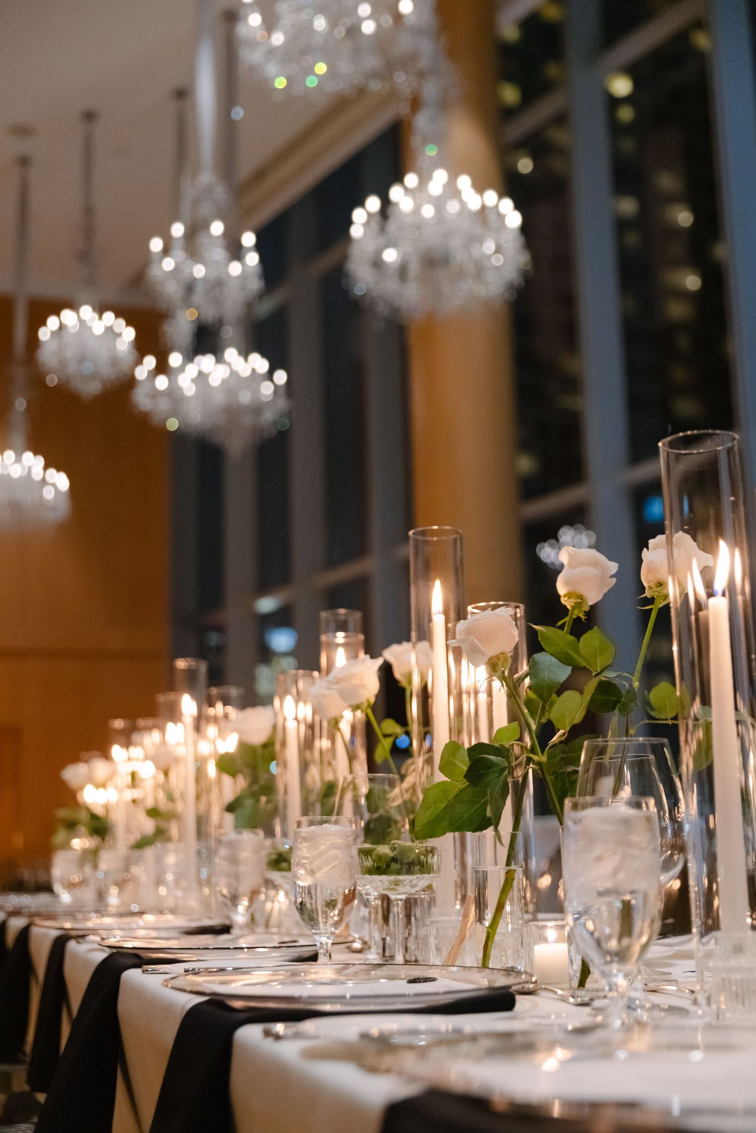 Elegant dining room with crystal chandeliers and candlelit tables adorned with roses.