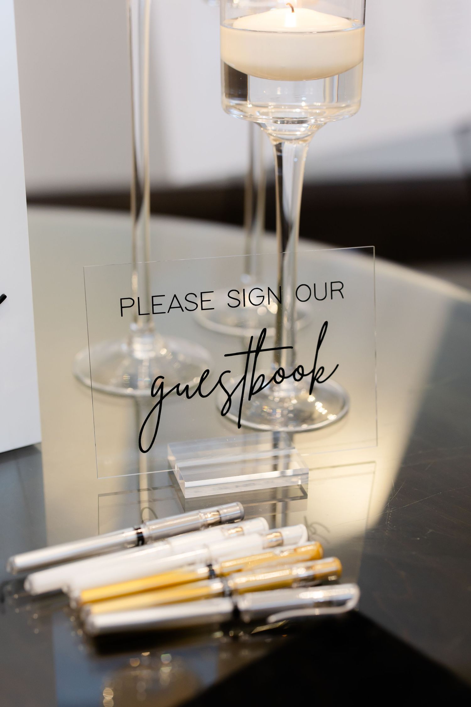 Guest book signing station with elegant floating candles and metallic pens.