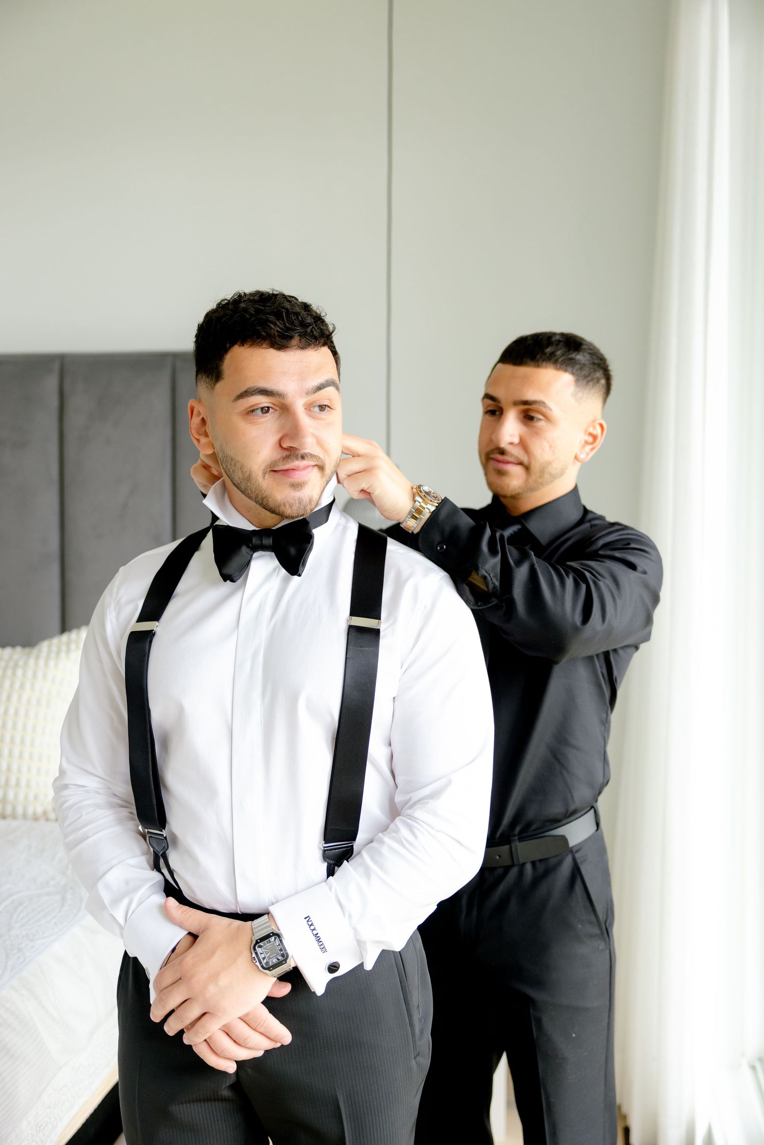 Wedding preparation scene showing formal attire with black suspenders being adjusted.