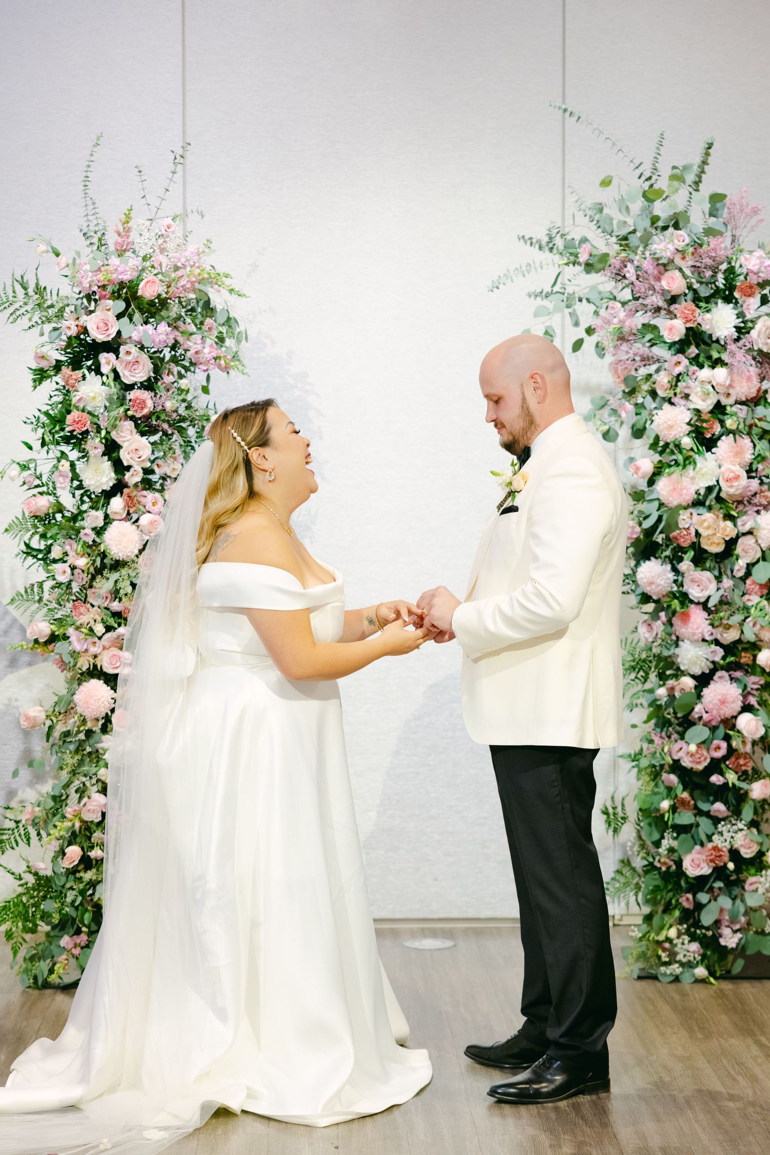 Wedding couple shares emotional exchange beneath romantic floral arches.
