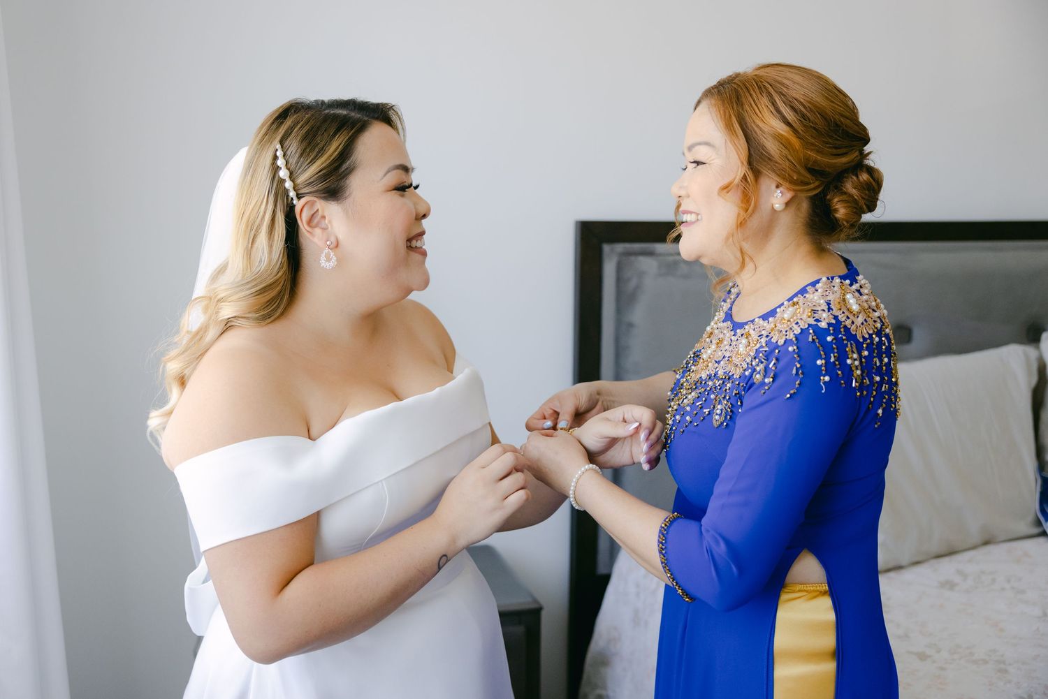 Two women share a joyful moment during wedding preparations in a bright room.