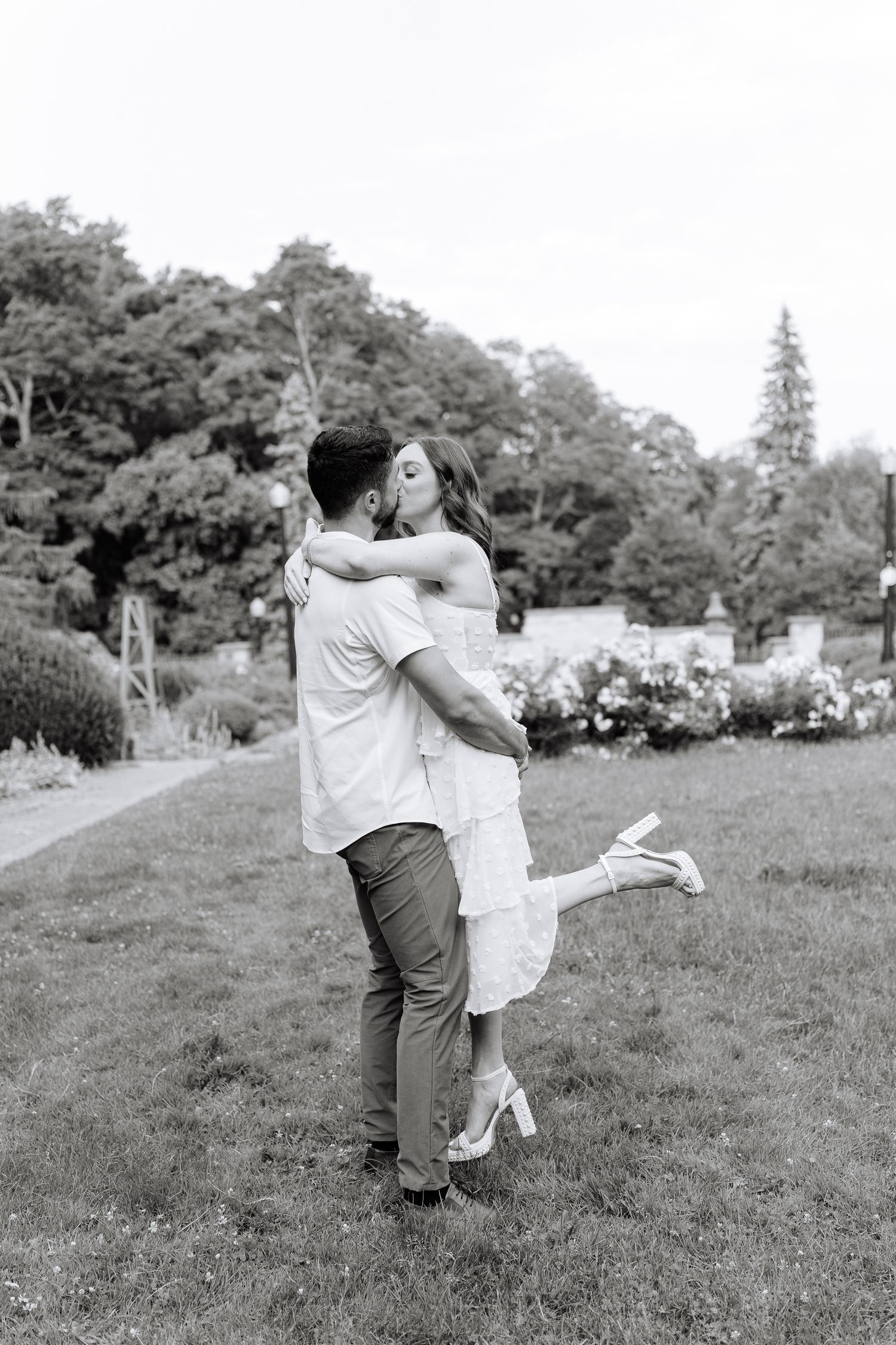 A romantic black and white photo of a couple embracing in a garden setting.