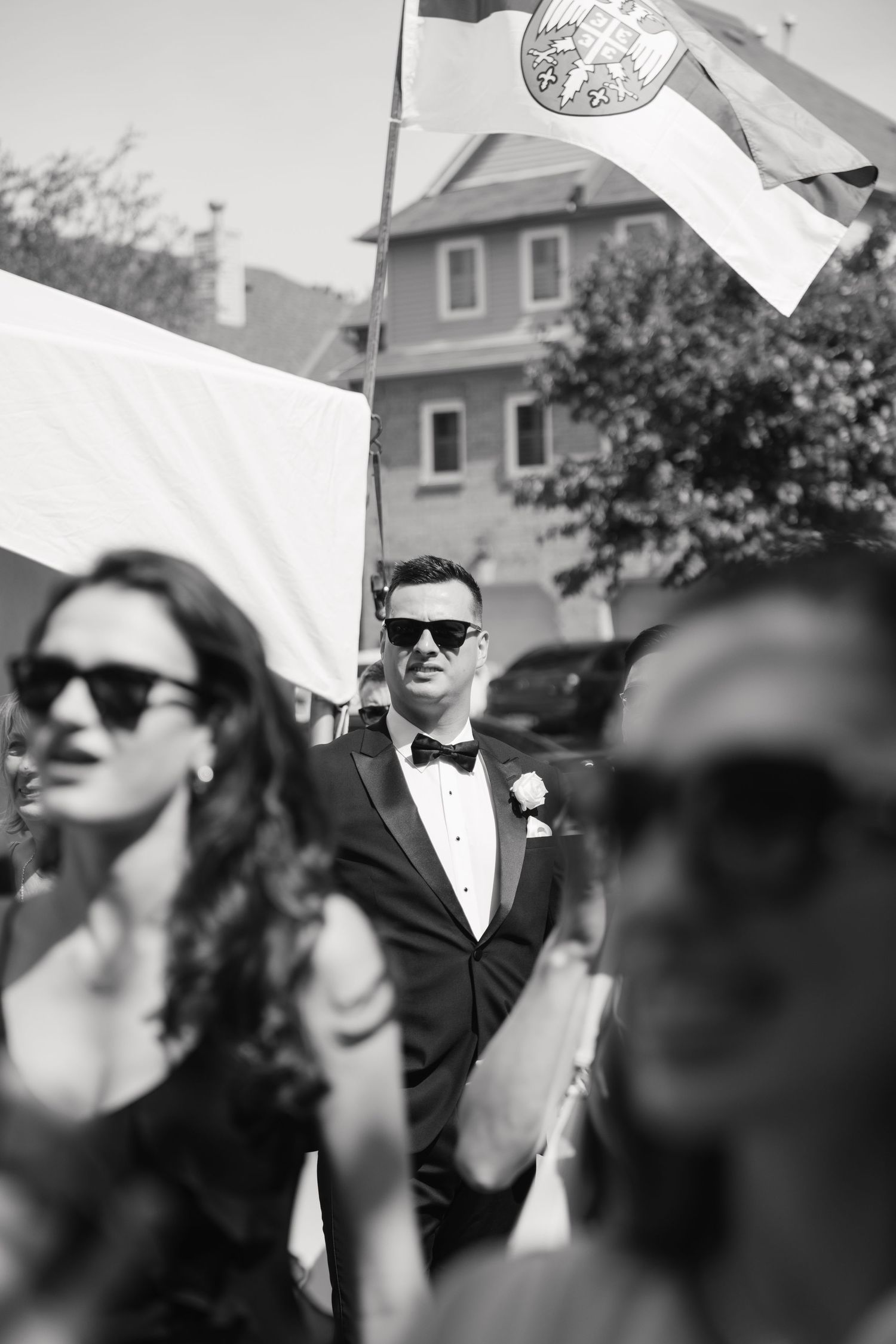 Black and white photo of wedding celebration with flags and sunglasses.