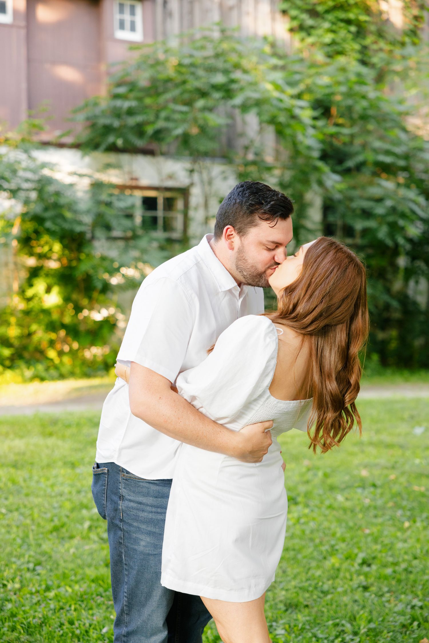 Couple in white embracing and sharing a tender moment in a garden setting.