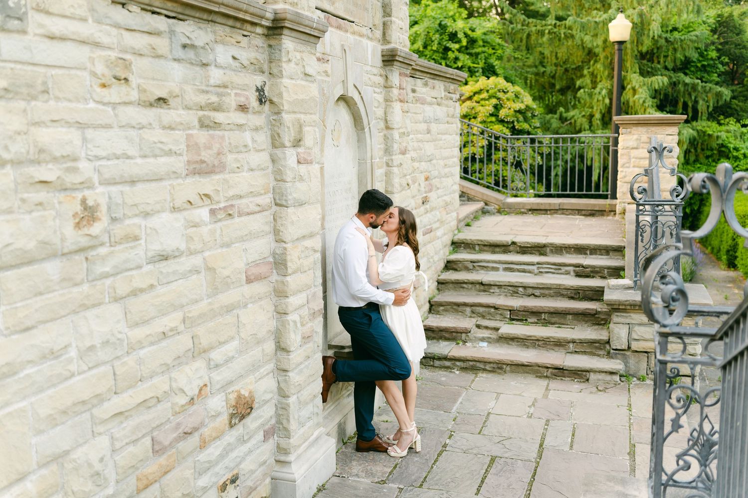 A couple shares a tender embrace near historic stone steps and ironwork.