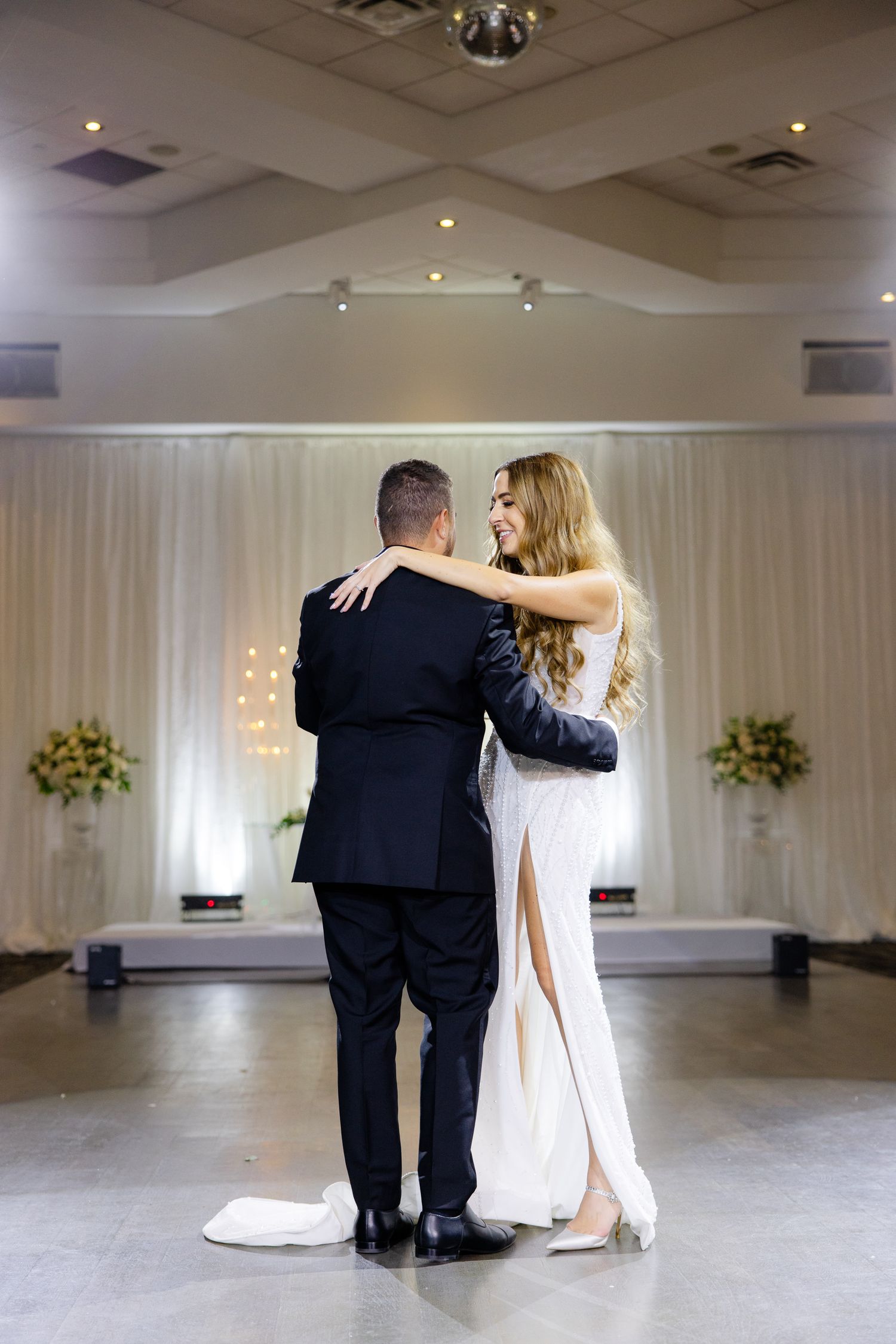 Elegant couple shares intimate slow dance in beautifully decorated reception venue.