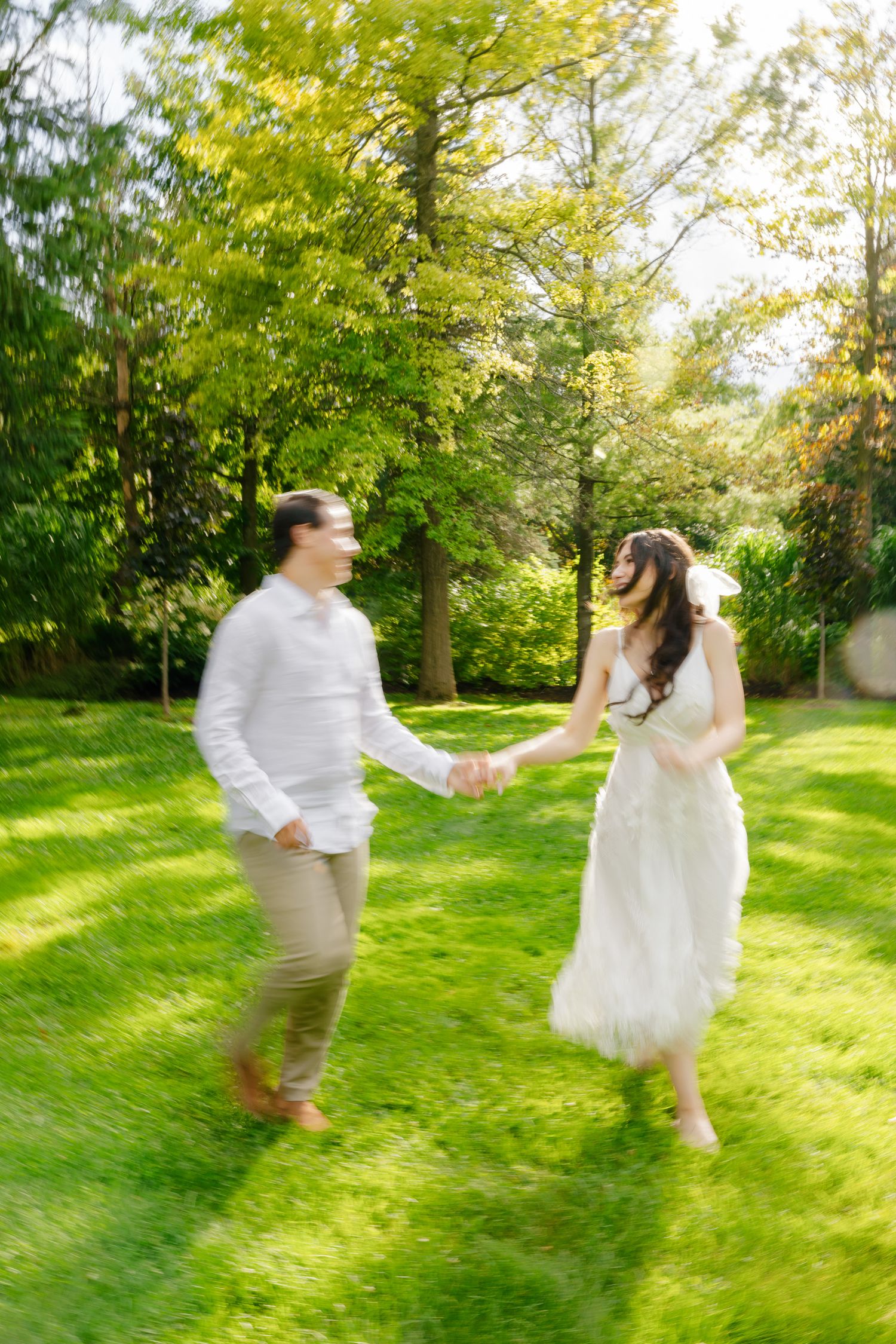 Motion-blurred photo of a couple dancing in a sunlit garden on their wedding day.
