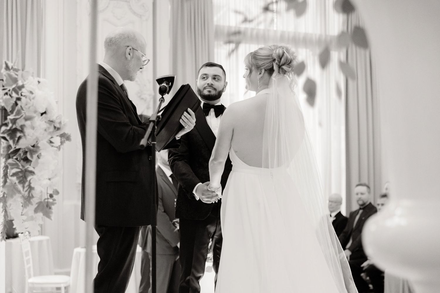 Black and white photo series showing elegant wedding moments in a bright ballroom setting.
