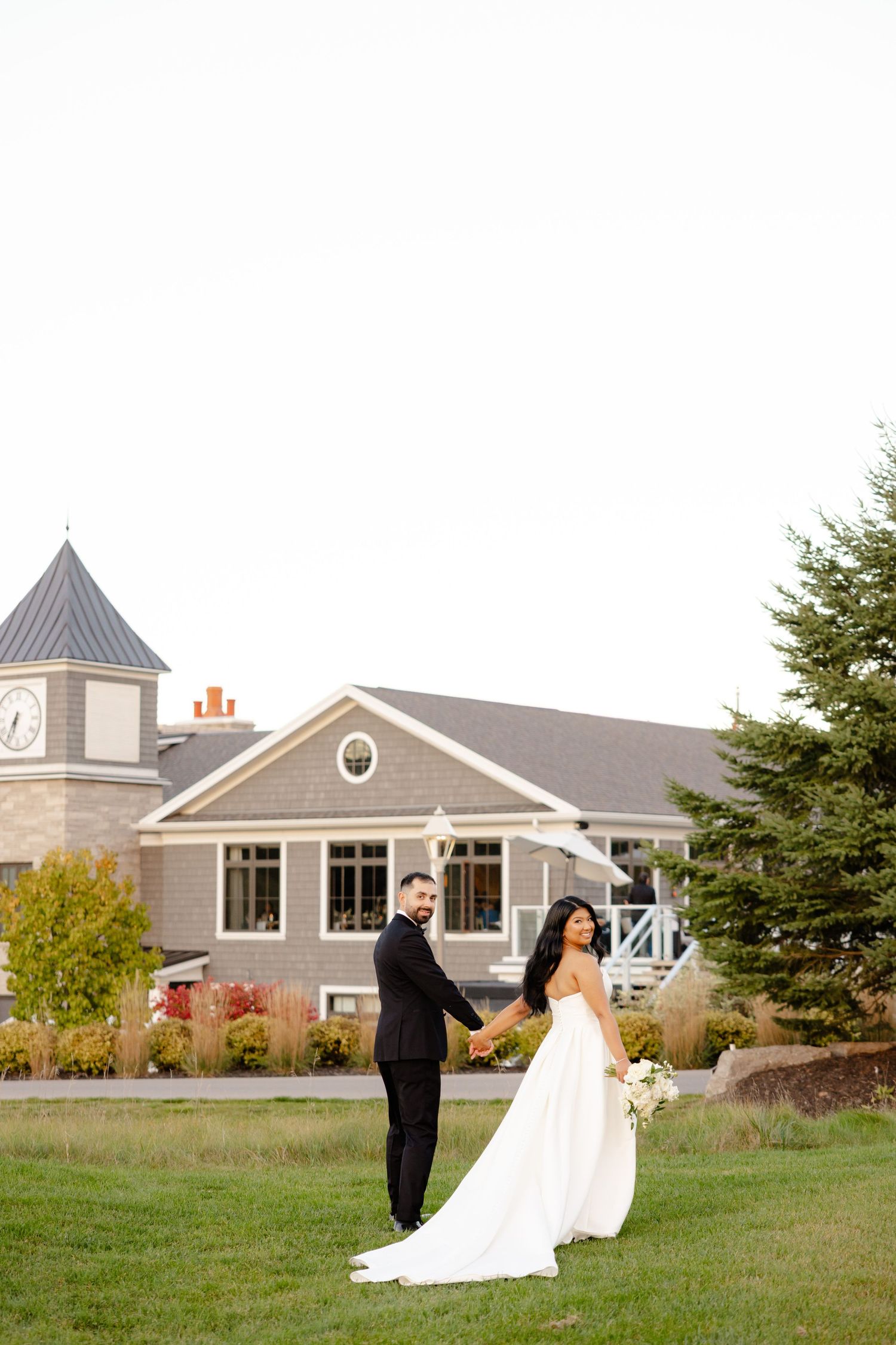A romantic wedding portrait with the couple holding hands against a stunning venue backdrop.
