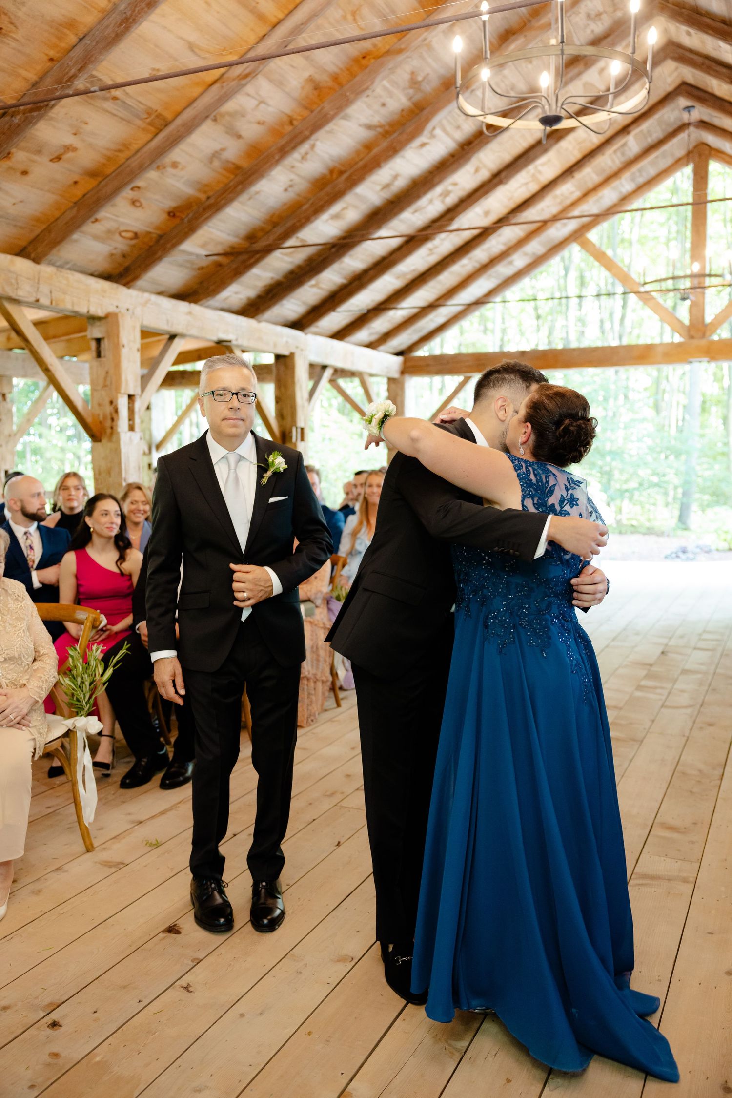 Emotional moment during wedding ceremony in rustic wooden venue with vaulted ceiling.