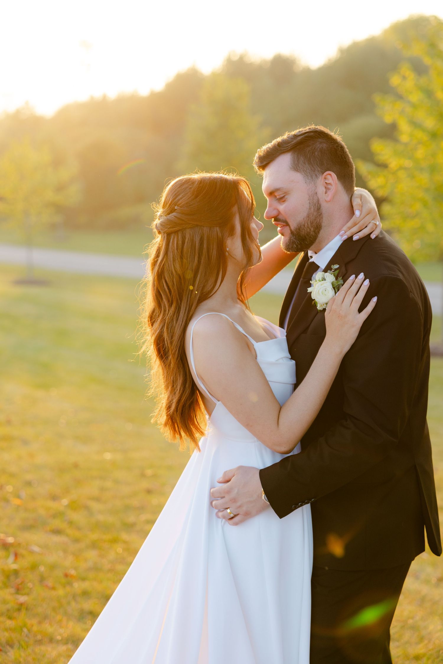 A wedding couple embraces during golden hour photography in an outdoor setting with autumn colors.