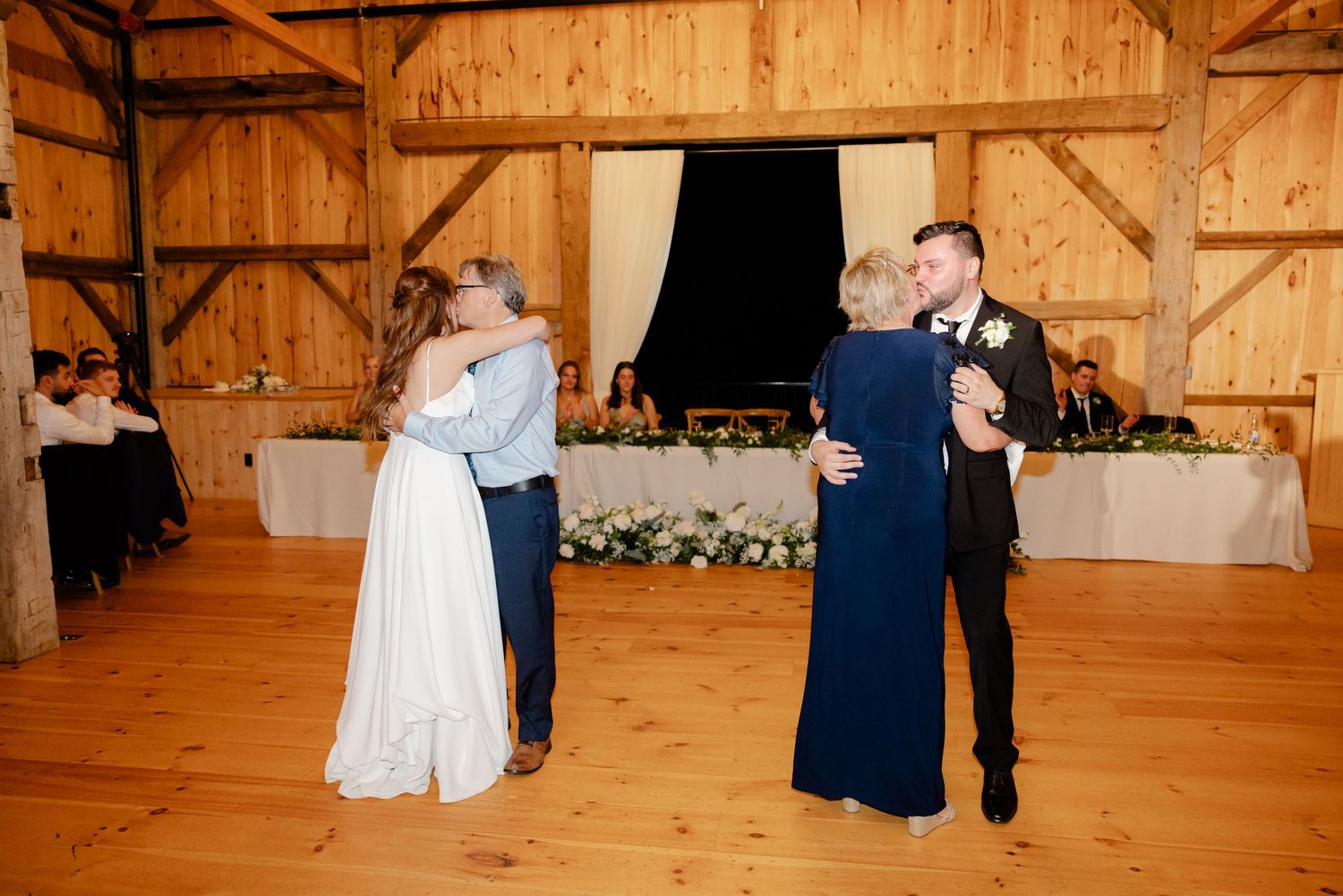 Couples share special dances at a rustic barn wedding with elegant floral decorations.