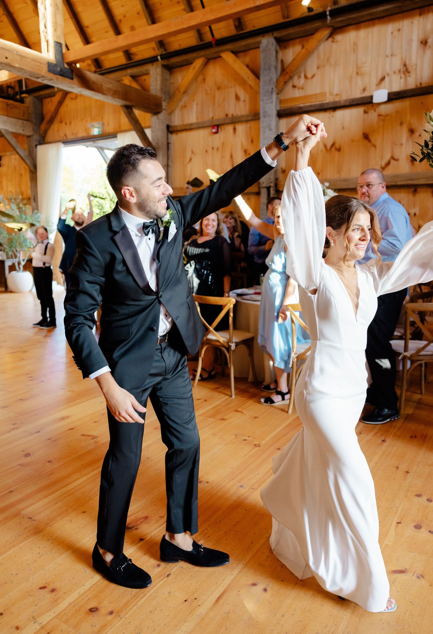 Newlyweds dancing together on wooden floors in a rustic barn reception venue.