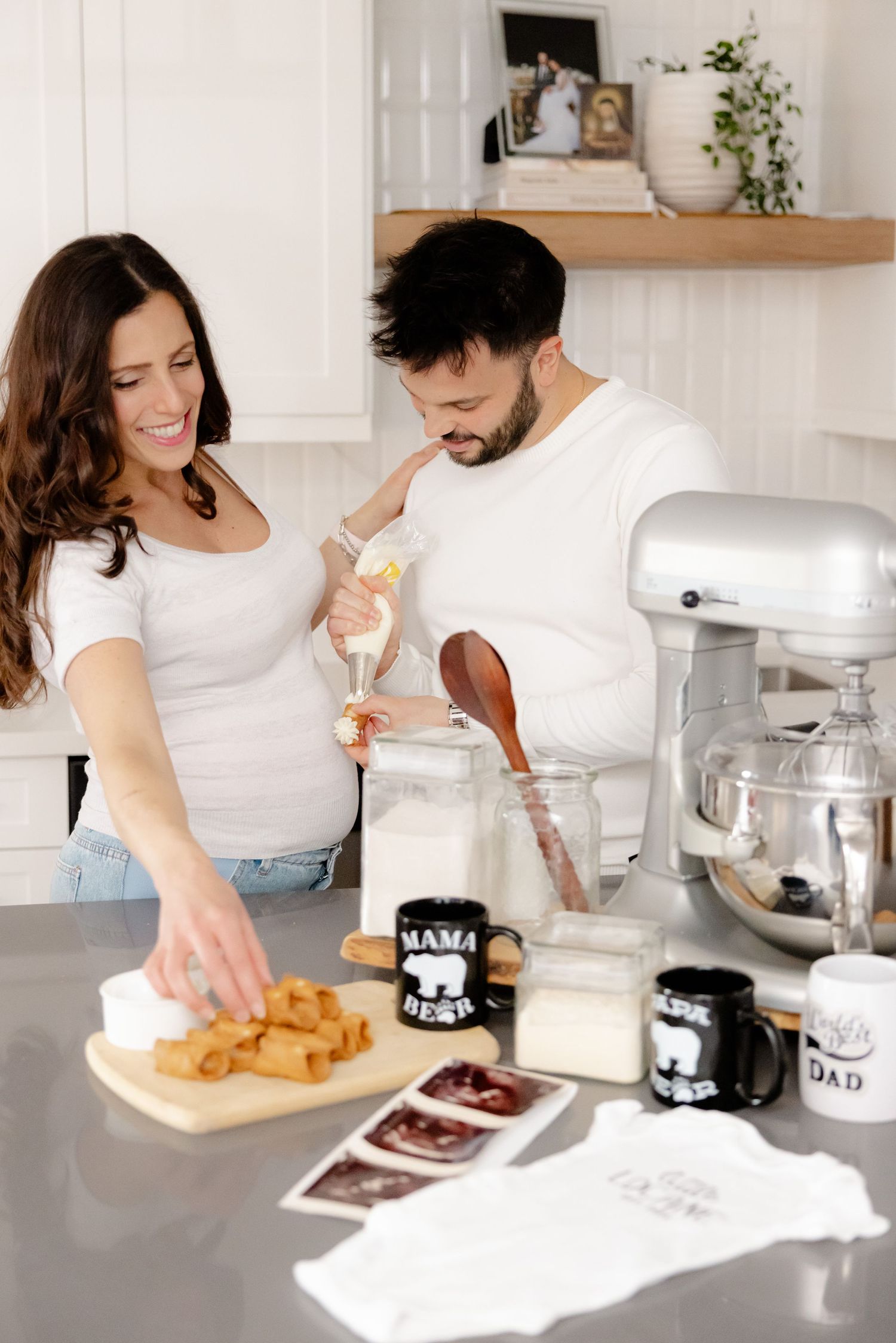 Couple baking together in a bright kitchen with a stand mixer and mugs on the counter.