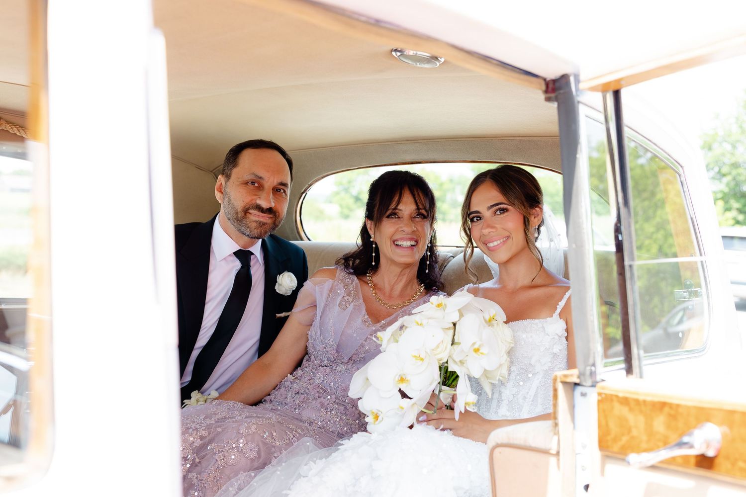 Five wedding guests share candid moments in the back of a wedding party vehicle during a celebration.