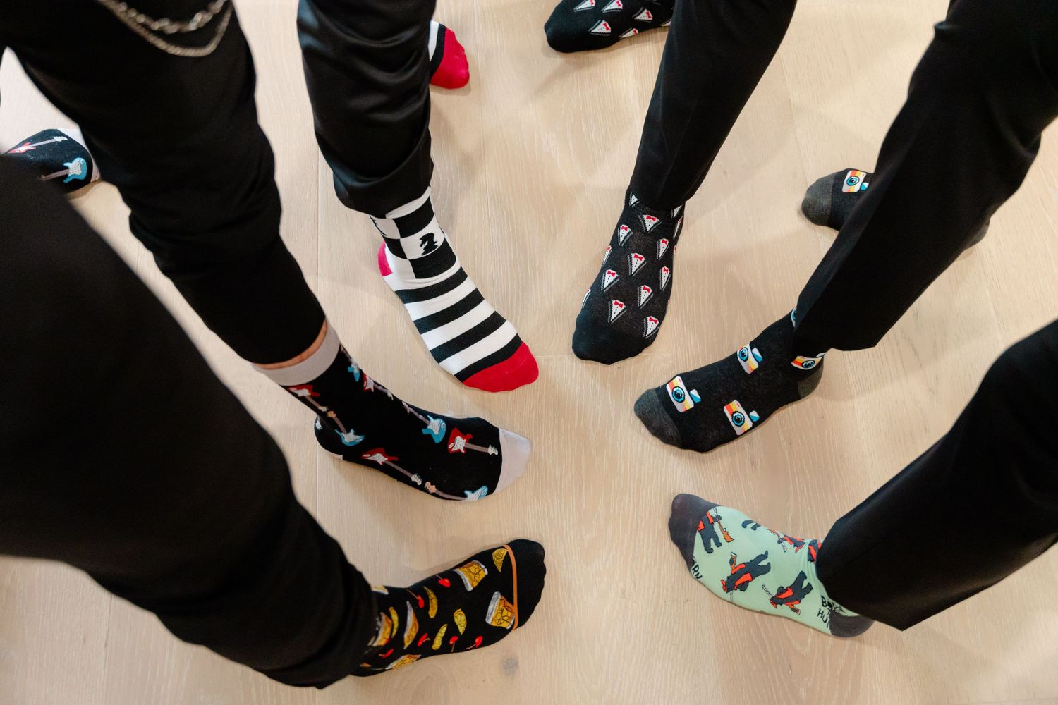 Groomsmen showing off their fun mismatched socks while wearing formal attire at a wedding.