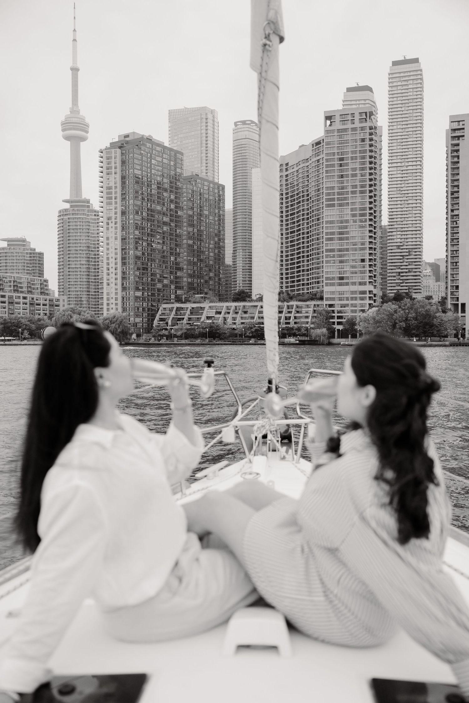 Two people sit on a boat overlooking Toronto's skyline with the CN Tower visible in the background.